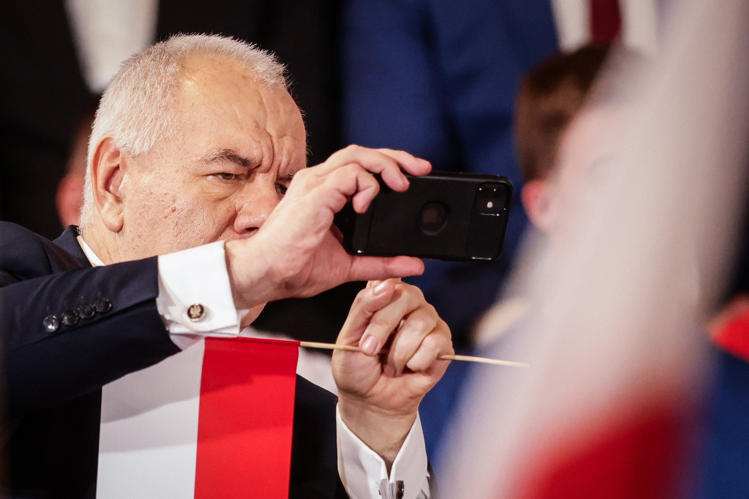 Mężczyzna, łysy, otyły, pokazuje coś palcami jednej ręki