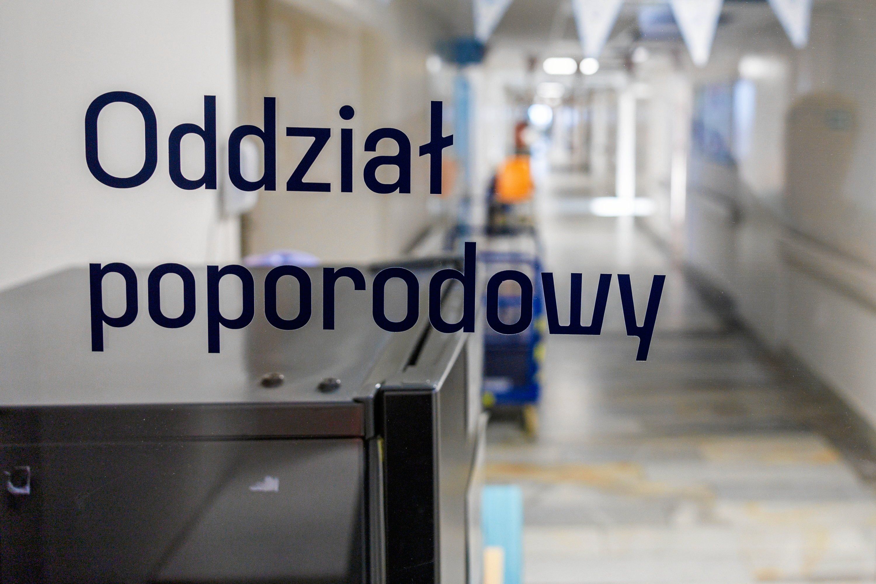 Szyba z napisem Oddział porodowy. W tle korytarz