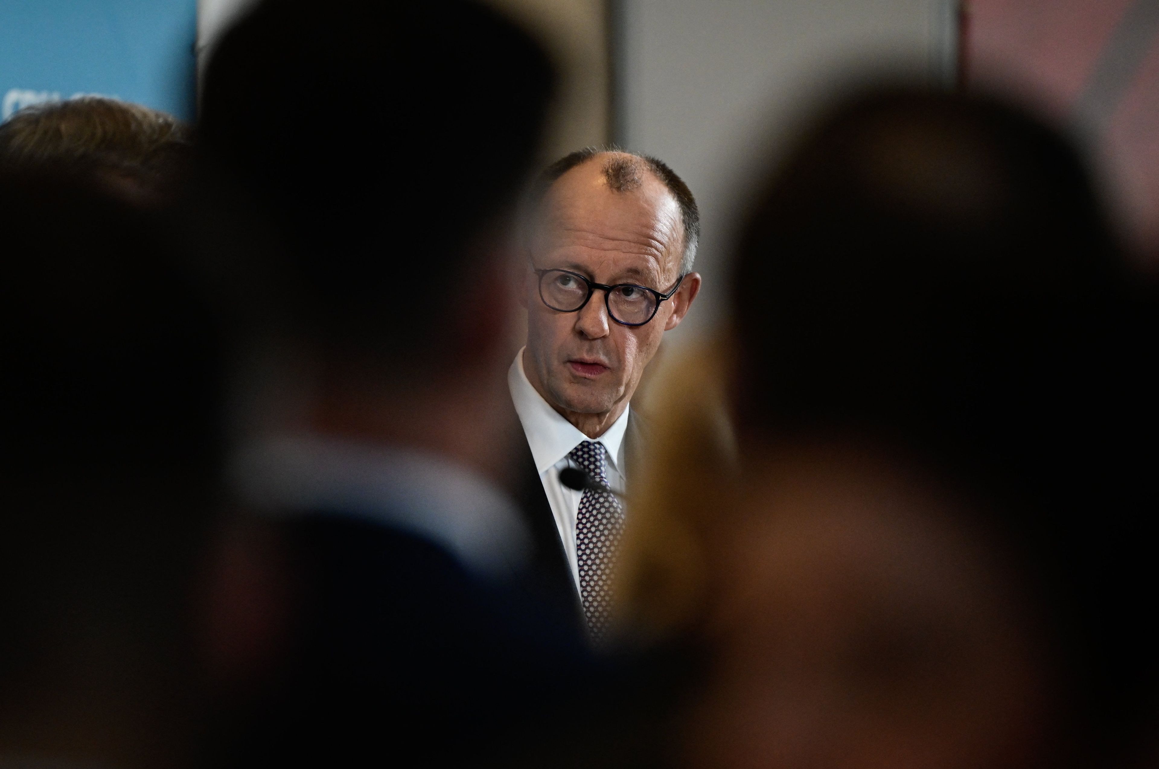 Twarz męzczyzny wyłania się zza sylwetek ludzi