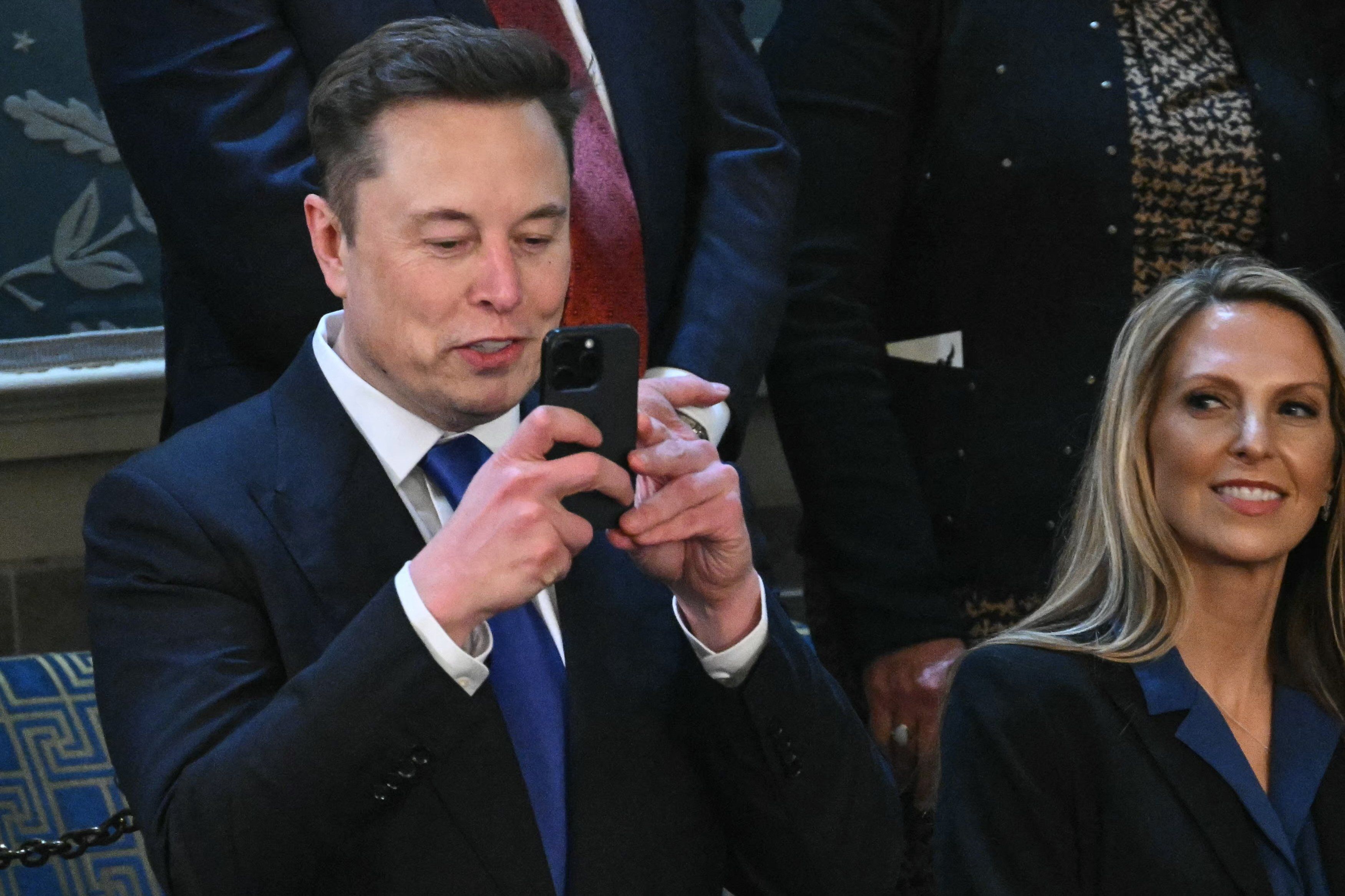 Mężczyzna przed pięćdziesiątką klika coś na telefonie albo robi zdjęcie. Elon Musk w amerykańskim Kongresie.