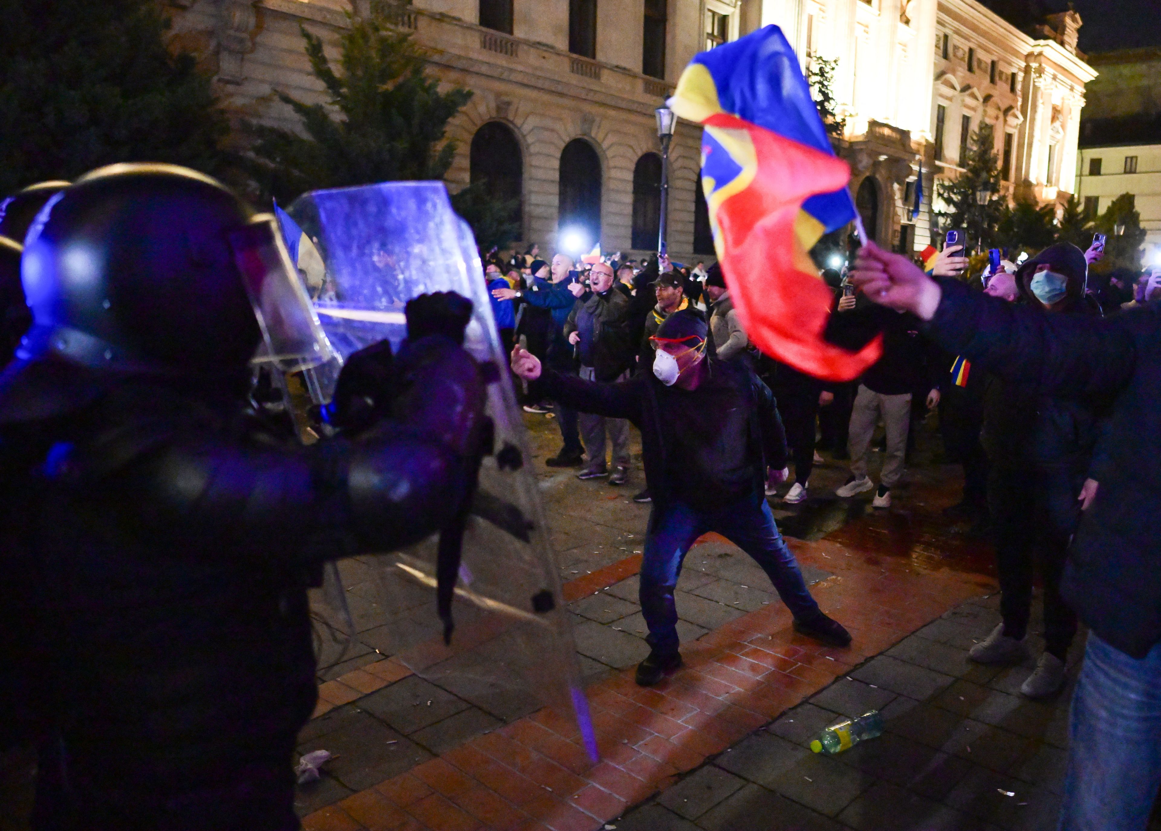 Noc. Protestujący z rumuńską flagą (żółto-czerowno-niebieską) i policjanci z tarczami