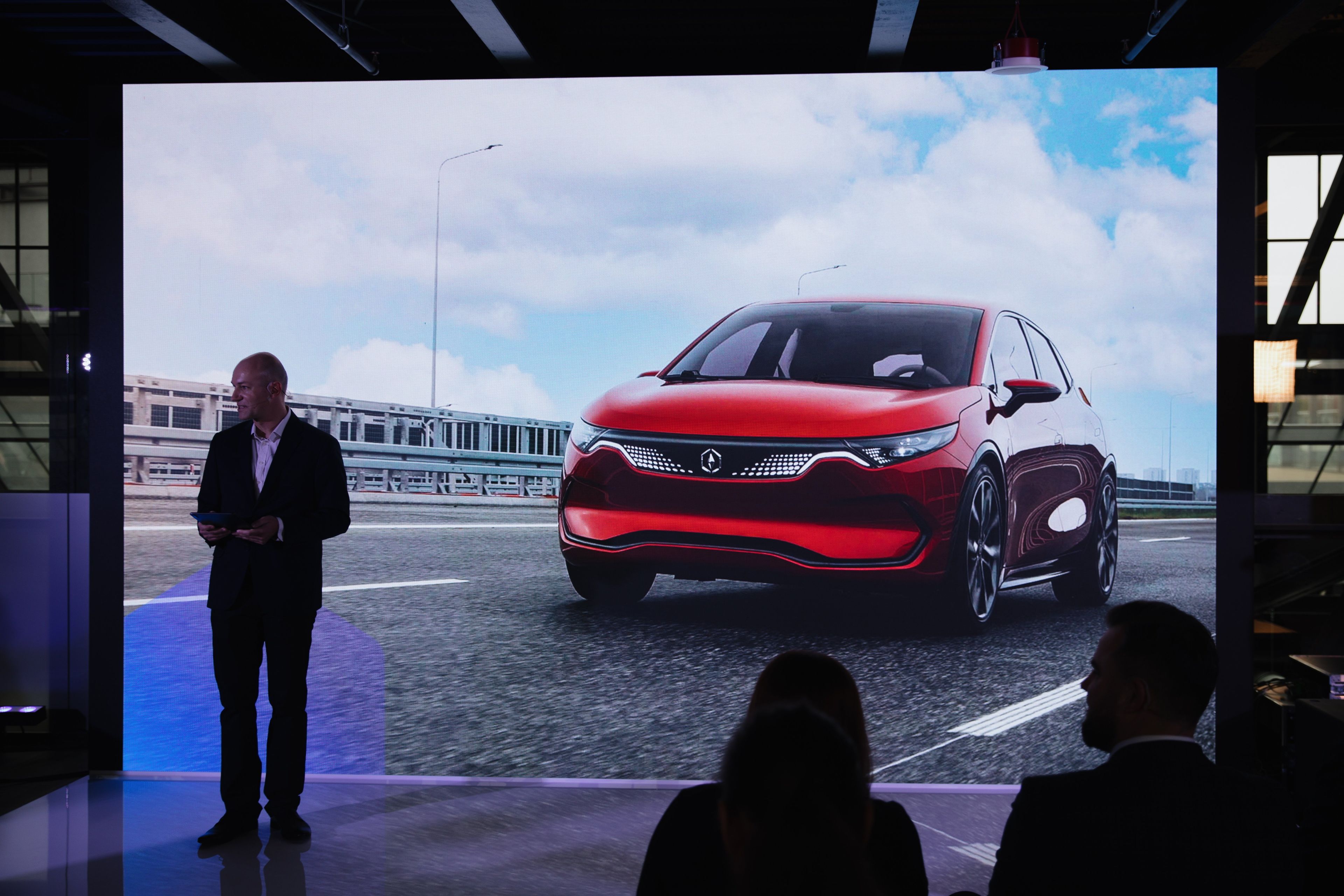 Mężczyzna stoi przed ekranem, na którym widać samochód