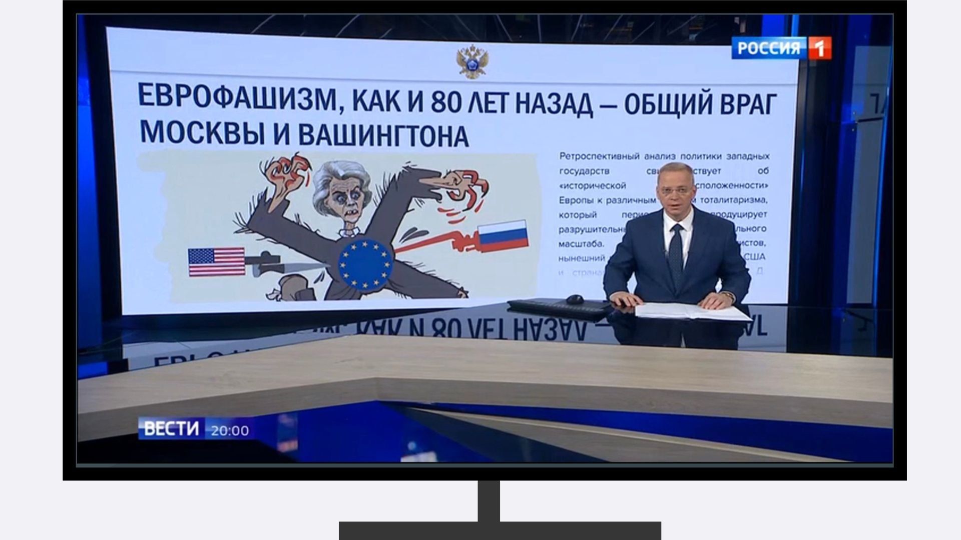 Grafika: w ramce telewizora zdjęcie ze strudia tv. Za porowadzącym grafika przedstawiająca bagnety z flagami rosyjską i amerykańska w sylwetkę Ursluli von den Leyen z sympolem UE i upozowaną jako swastyka