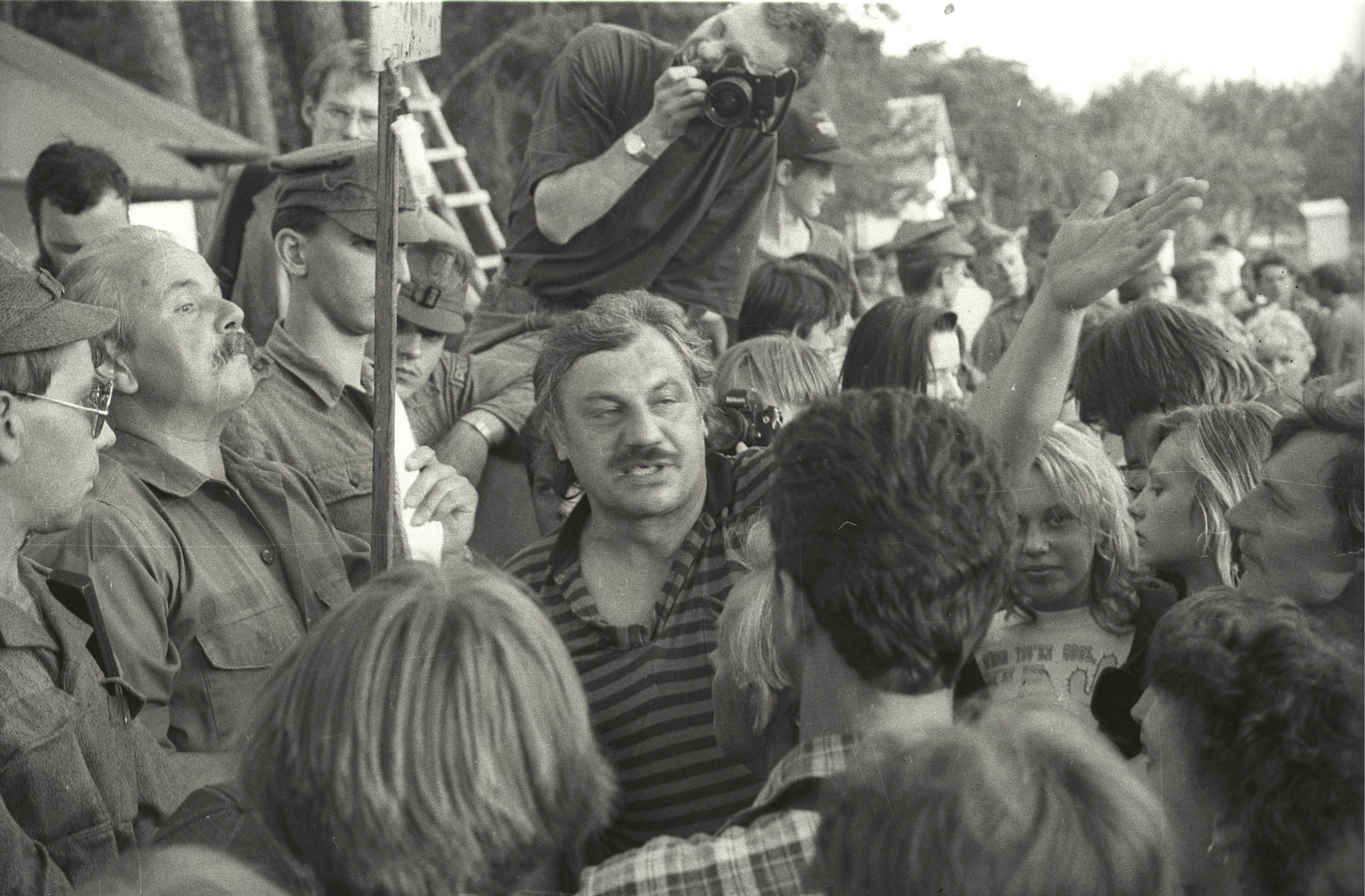 Tłum napierający na mężczyznę z wąsem bronionego przez żołnierzy.