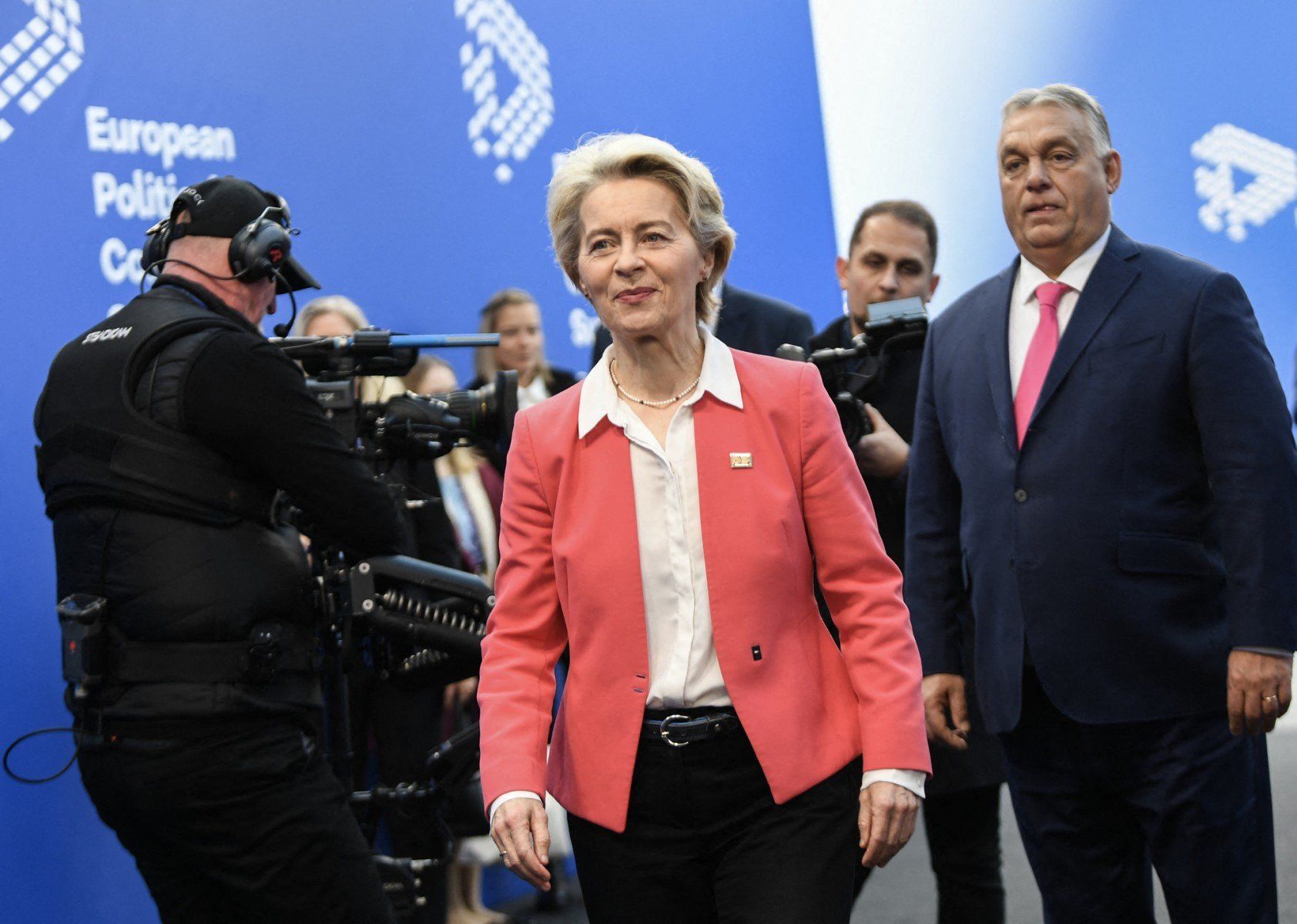 ursula von der leyen i stojący za nią voktor orban w korytarzu podczas szczytu ue