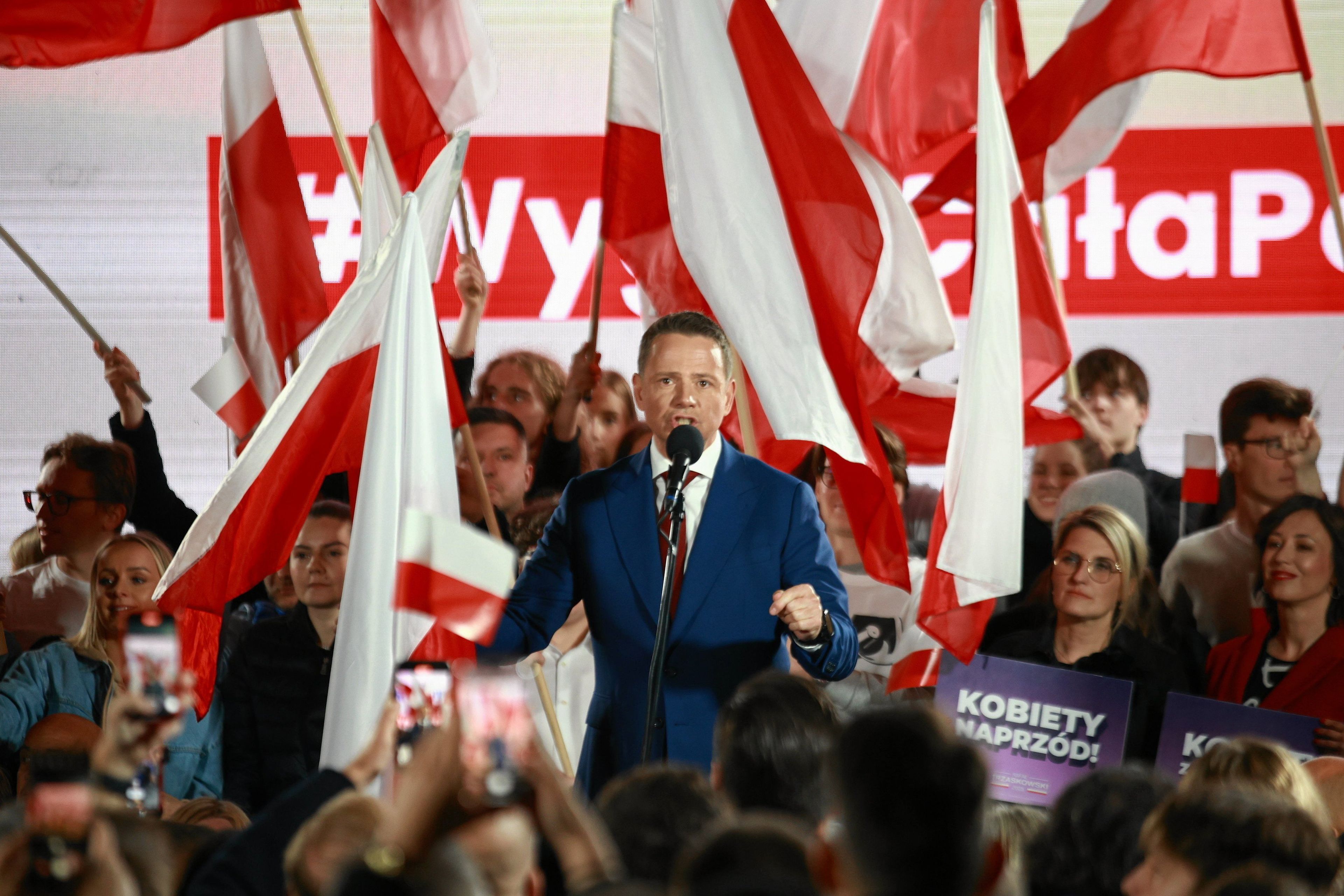 MężczyzNa przemawia w tle wiele białoczerwonych sztandarów