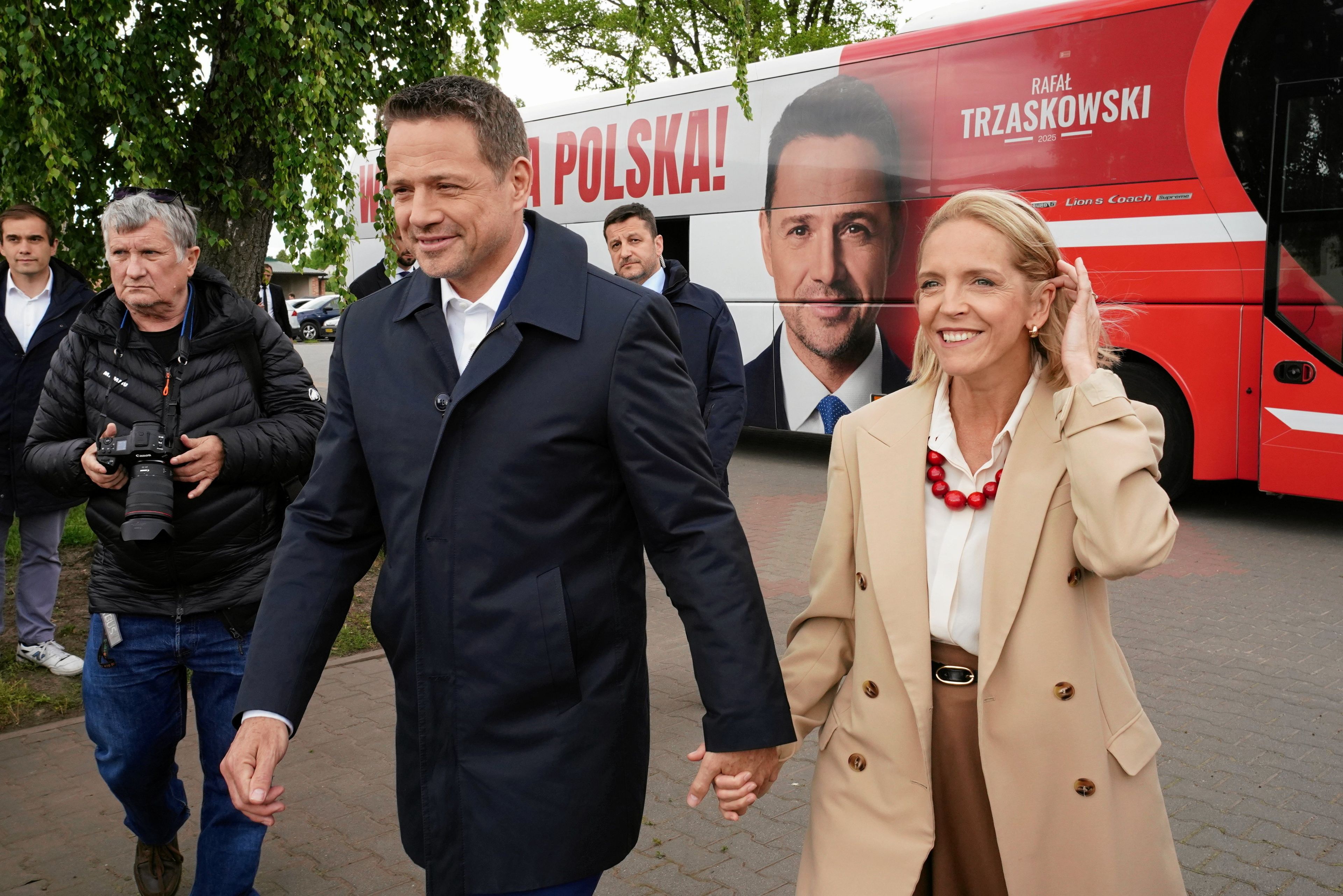 Rafał Trzaskowski trzyma za rękę żonę Małgorzatę. W tle autobus kampanijny