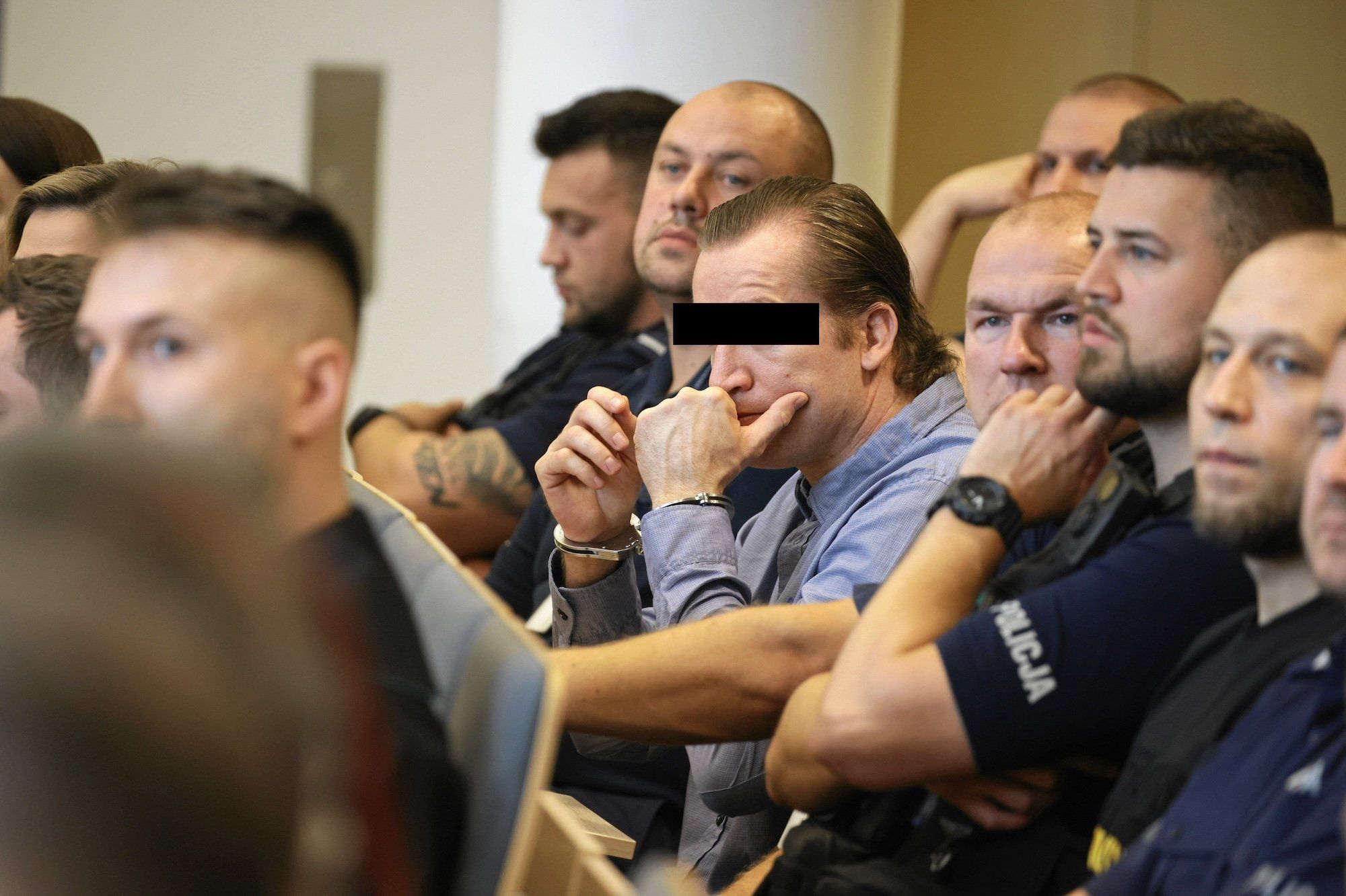 Mirosław O. "Olaf" podczas procesu przed Sądem Okręgowym w Poznaniu w 2022 roku. Na twarzy ma czarny pasek, ukrywający jego wizerunek. Na rękach widać kajdanki.