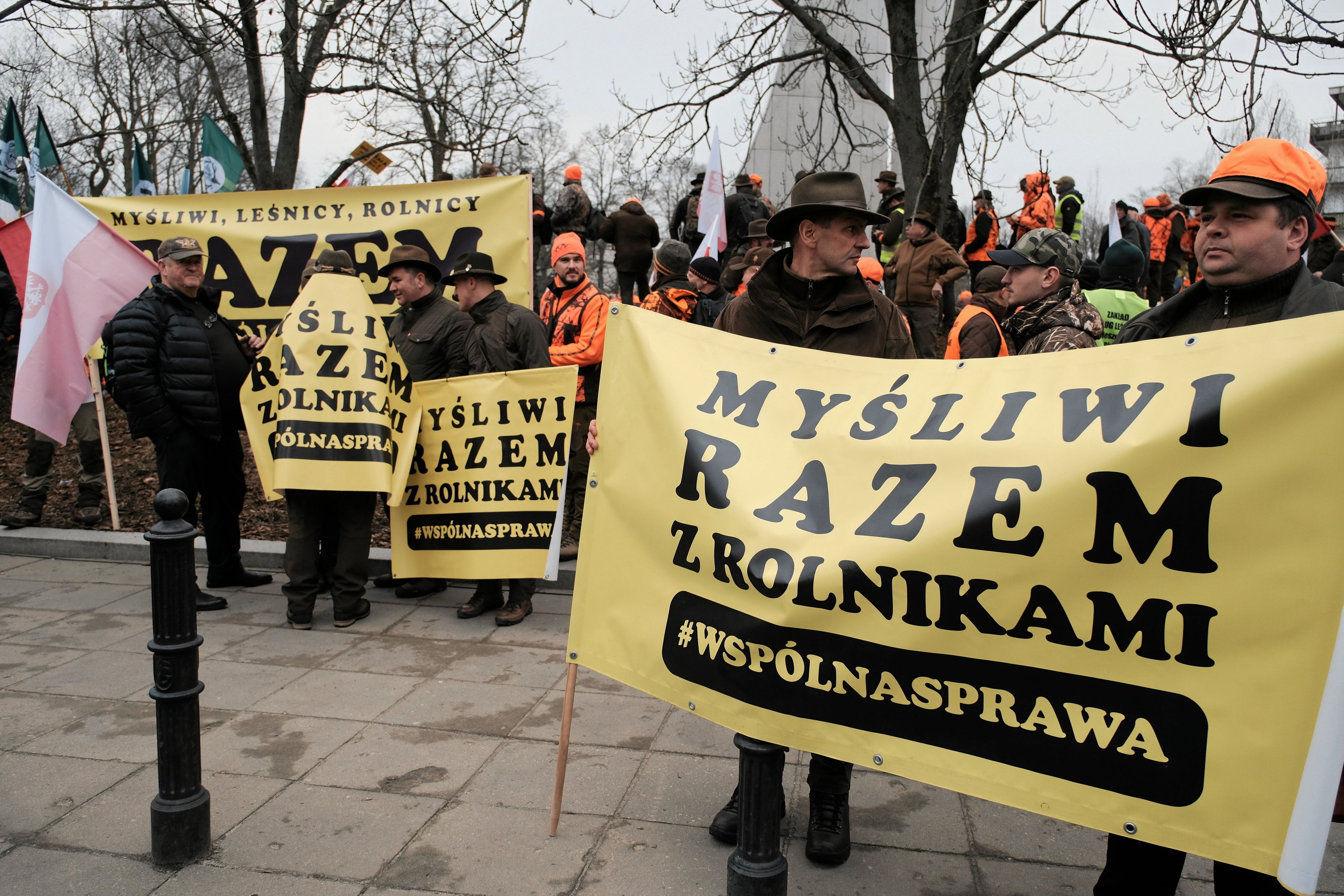 myśliwi protestują z żołtymi banerami z napisem "myśliwi razem z rolnikami, wspólna sprawa"