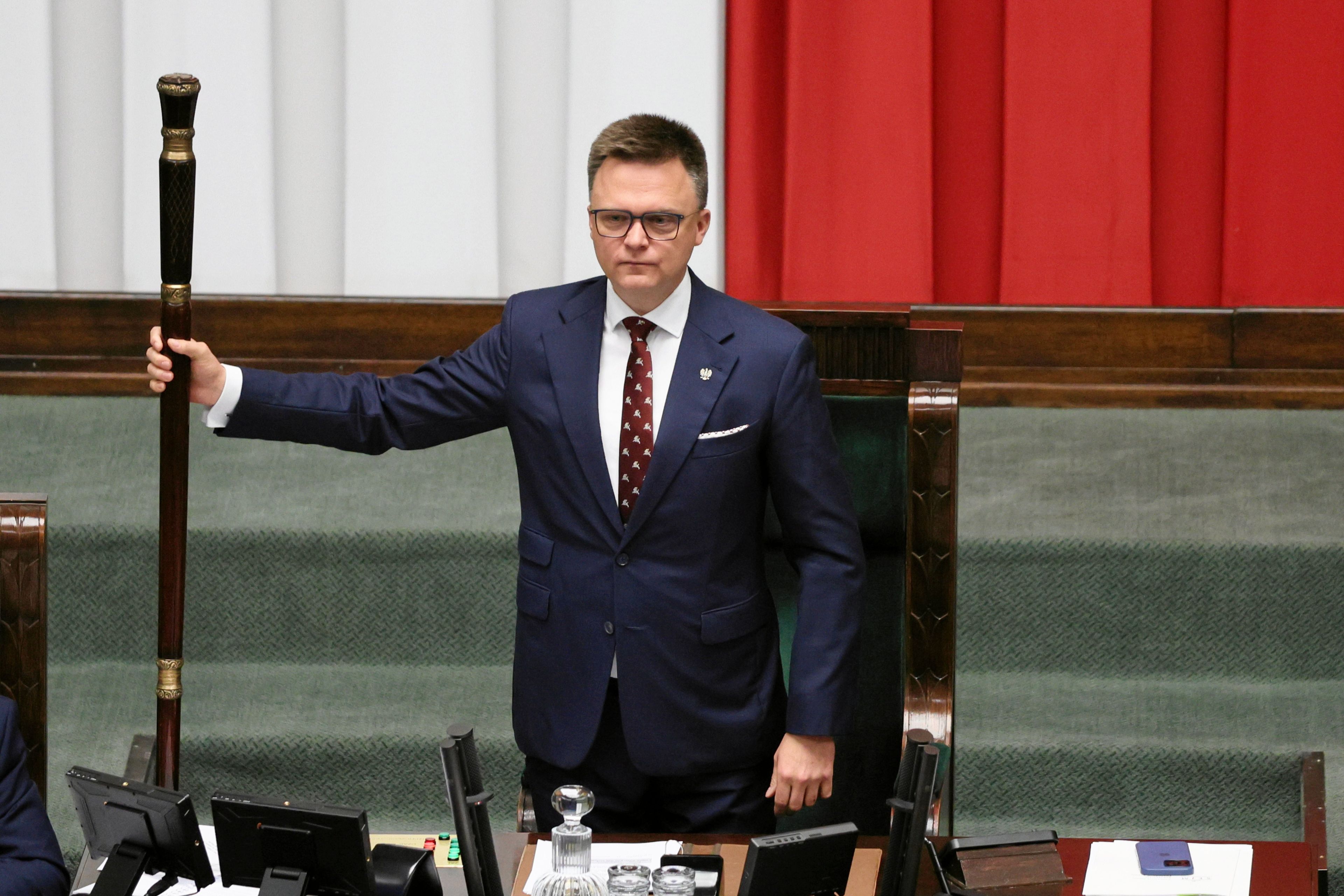 Mężczyzna stoi przy podium dla marszałka w Sejmie z laską marszałkowską