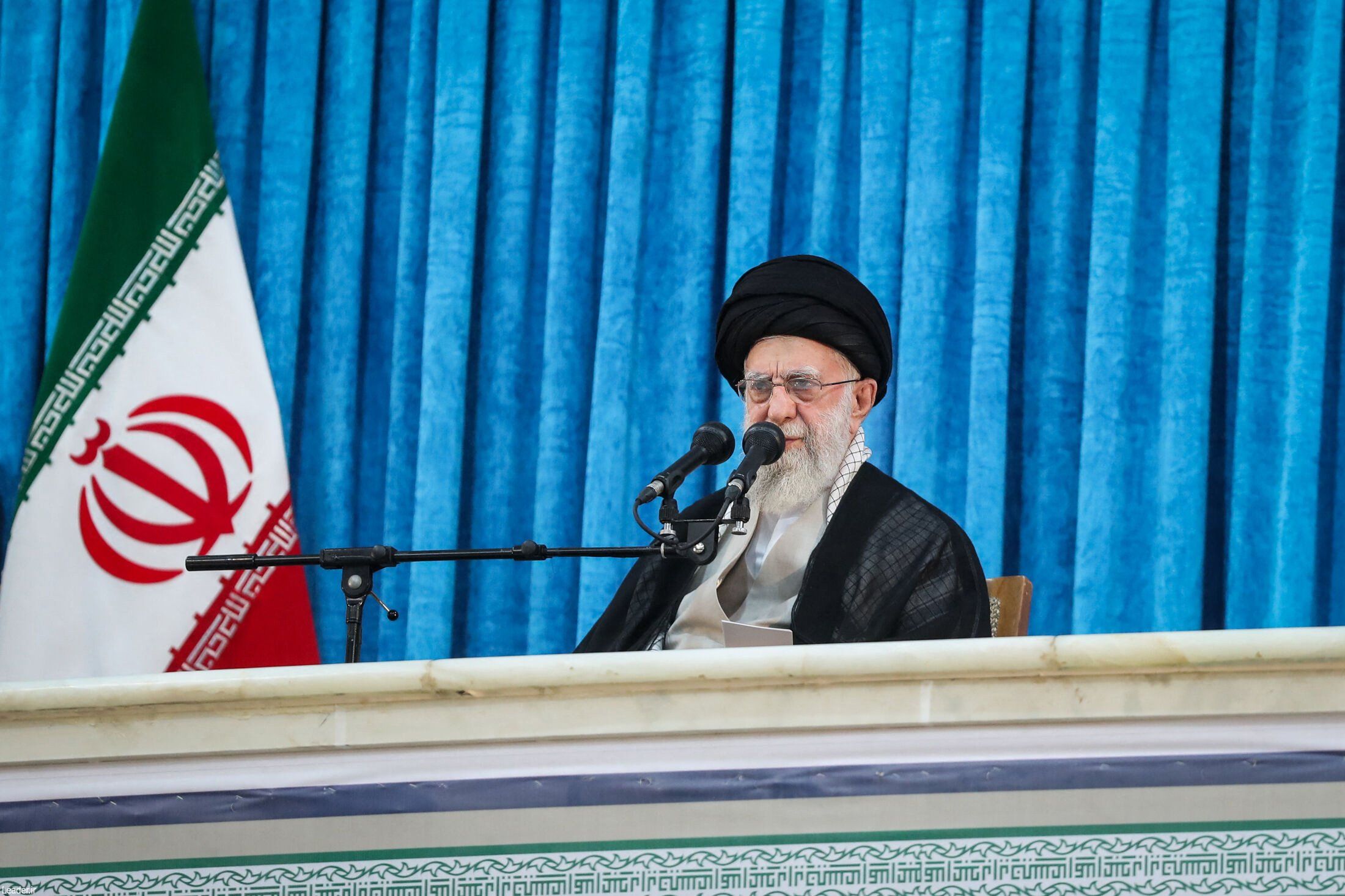 Ali Chamenei w czarnym turbanie przemawia na tle niebieskiej tkaniny