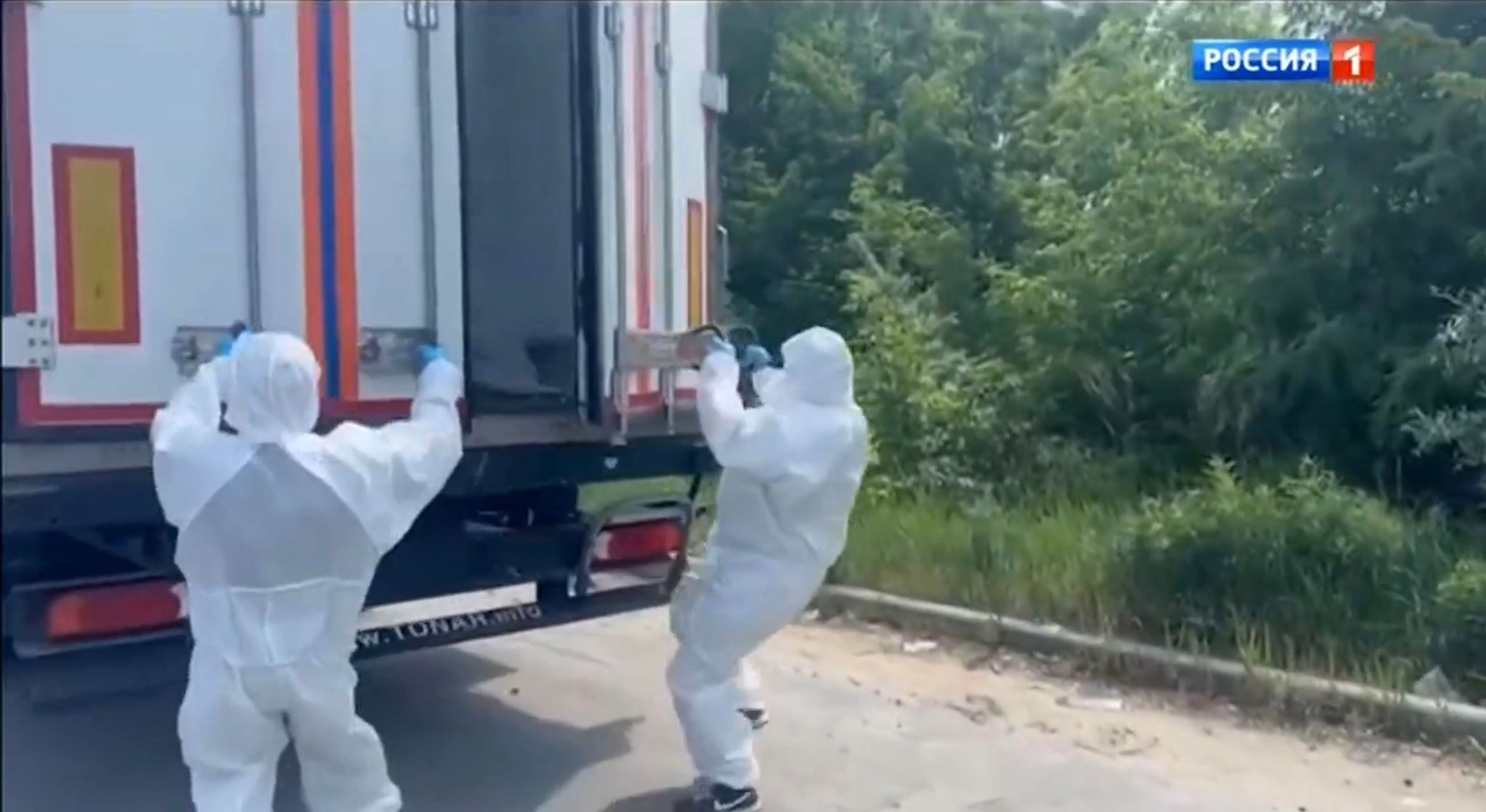 Ludzie w białych kombinezonach uchylają drzwi ciężarówki-chłodni
