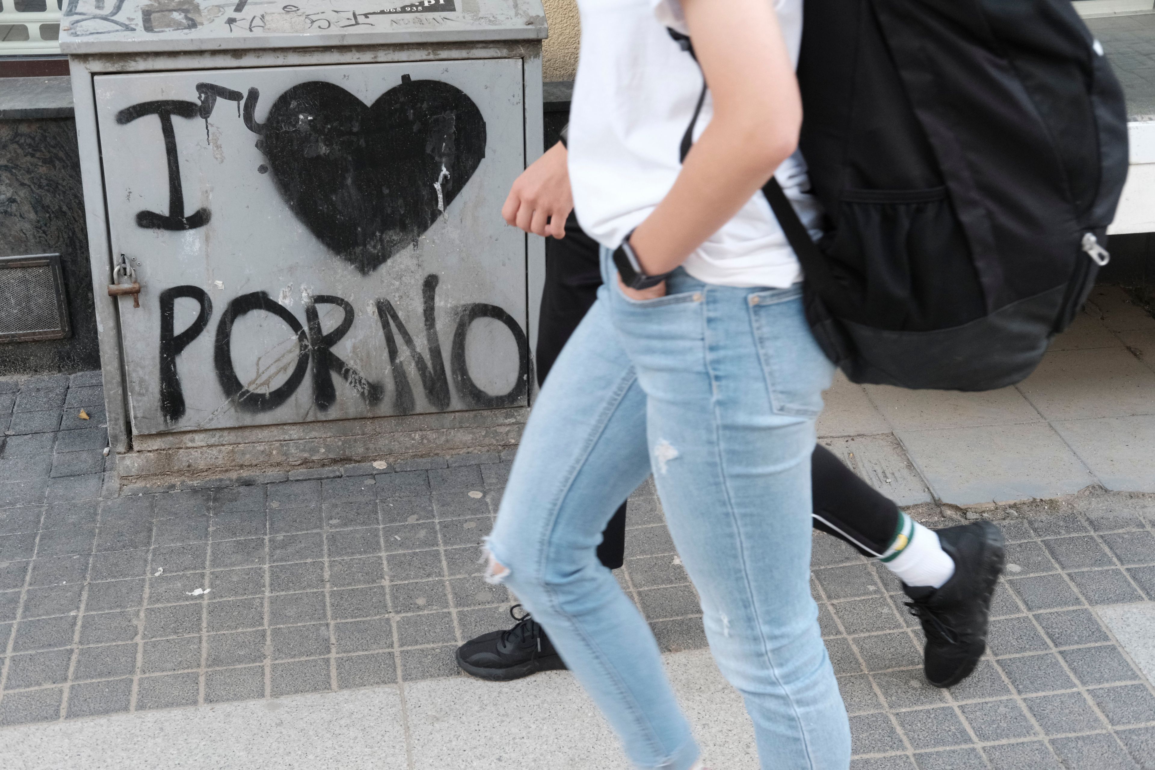 Postać przechodząca obok grafitti „I love porno"
