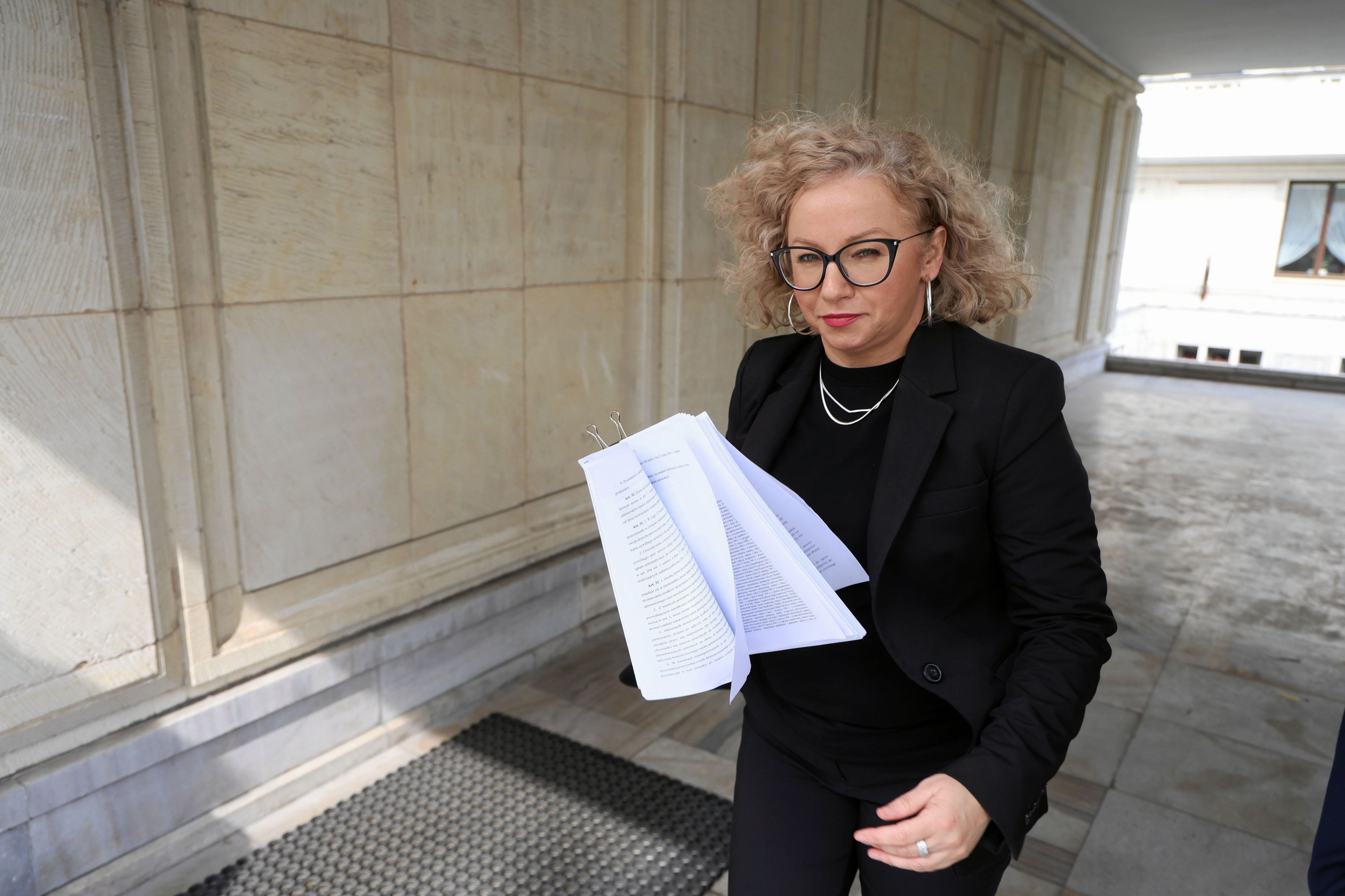 Katarzyna Kotula idzie z plikiem papierów w dłoni