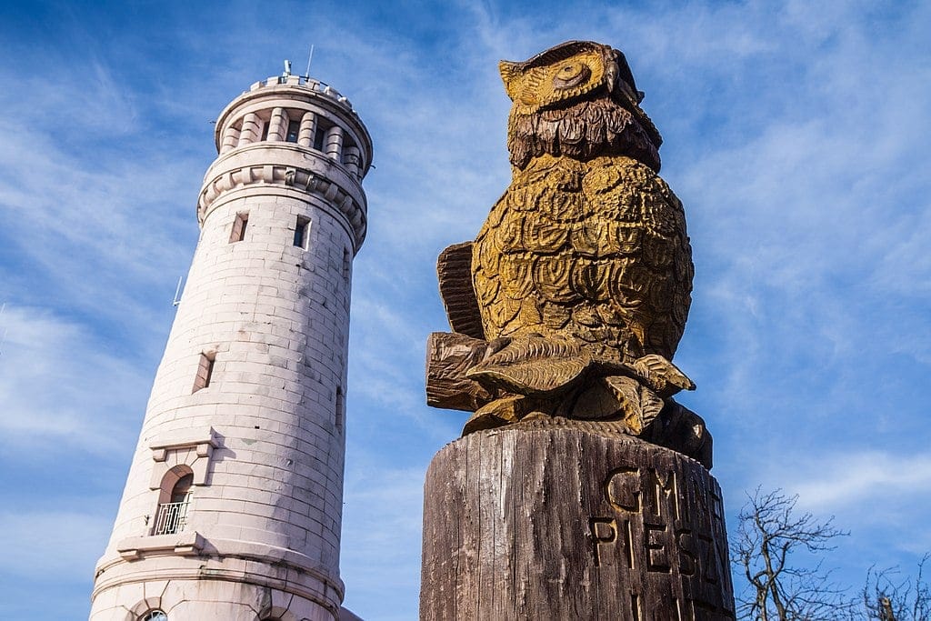 Okrągła wieża i drewniana figurka sowy.