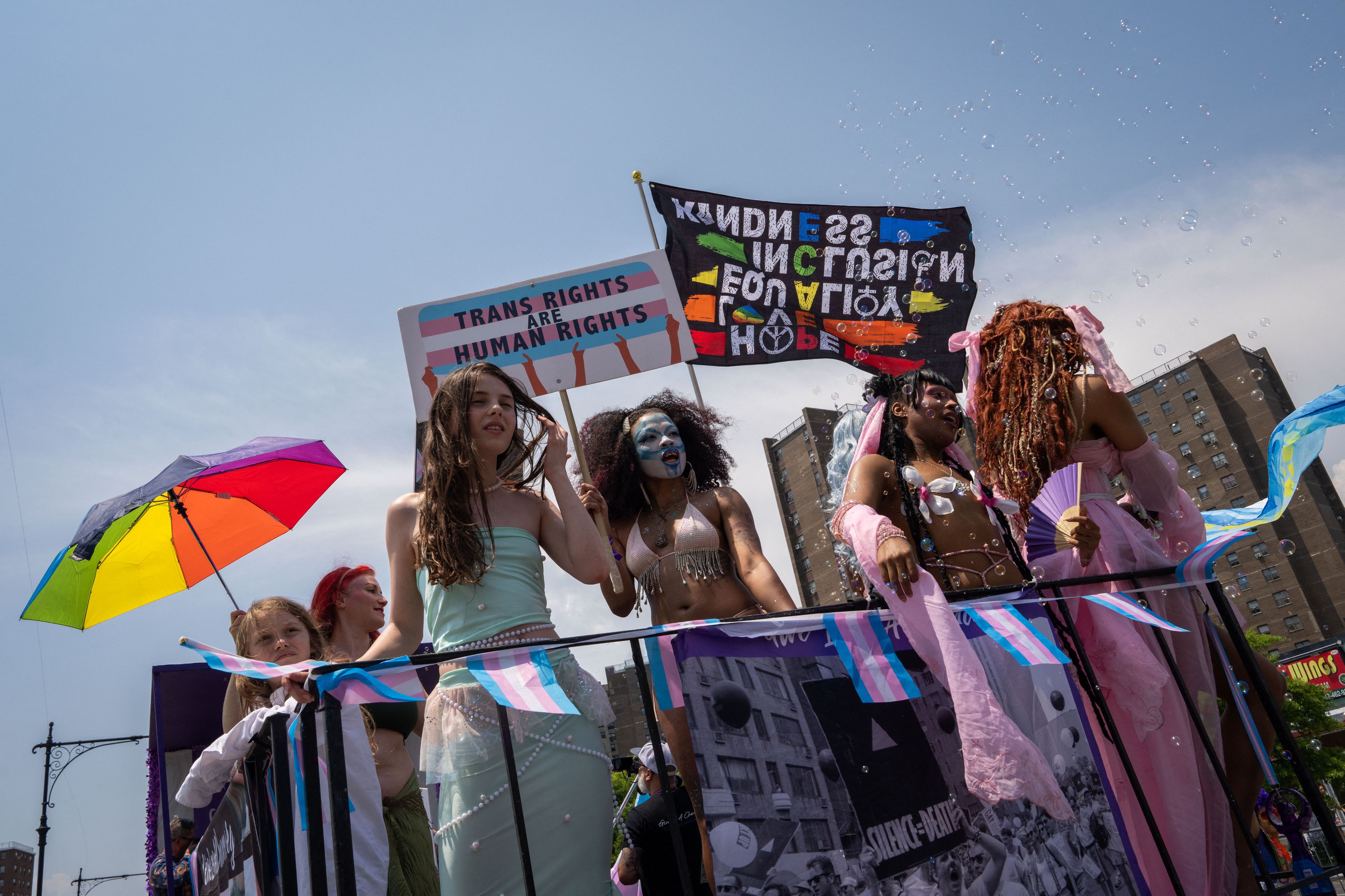 Kolorowo ubrane osoby z transparentami na rzecz praw osób transpłciowych.