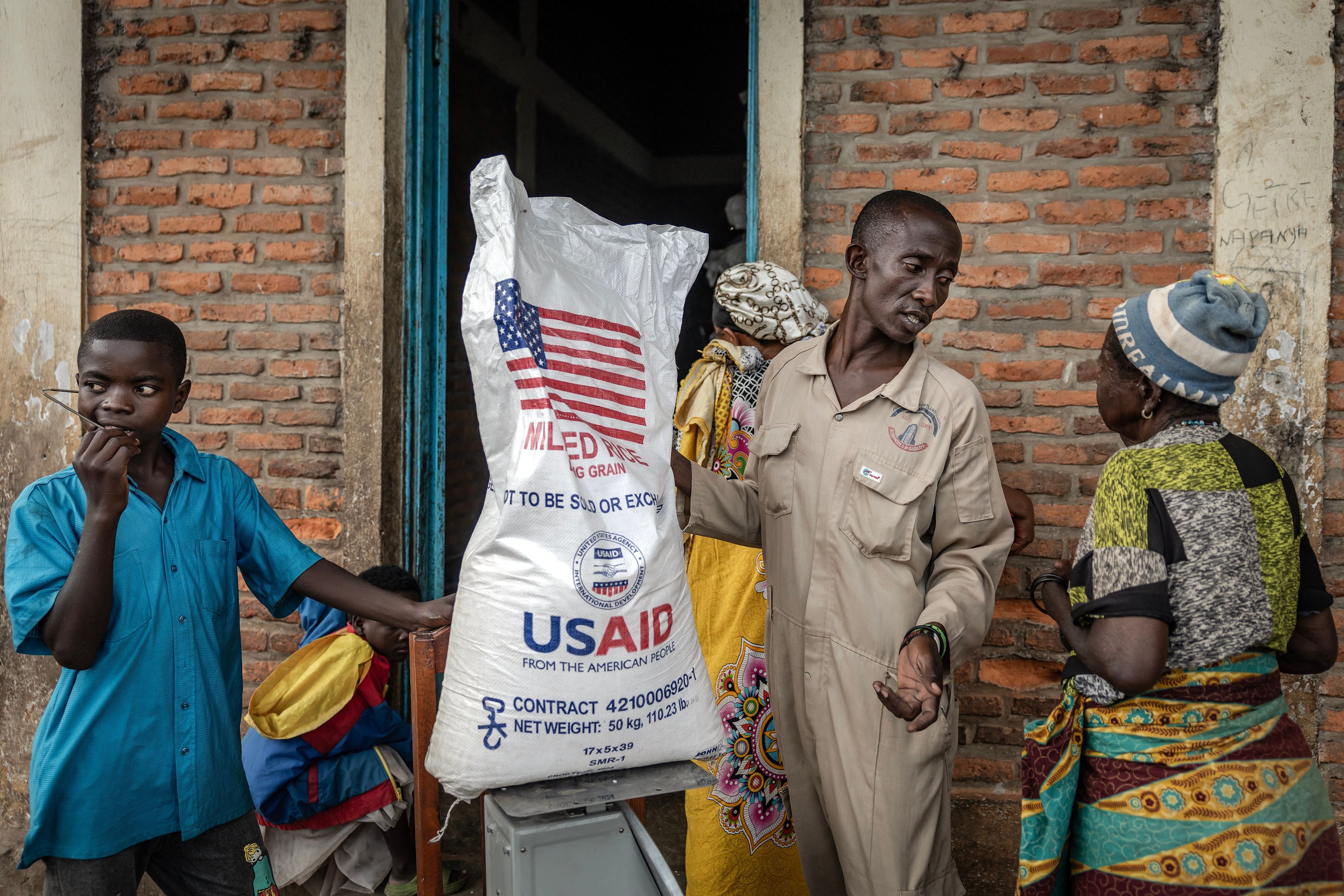 Grupa ludzi przy dużym worku z ryżem z napisem USAID