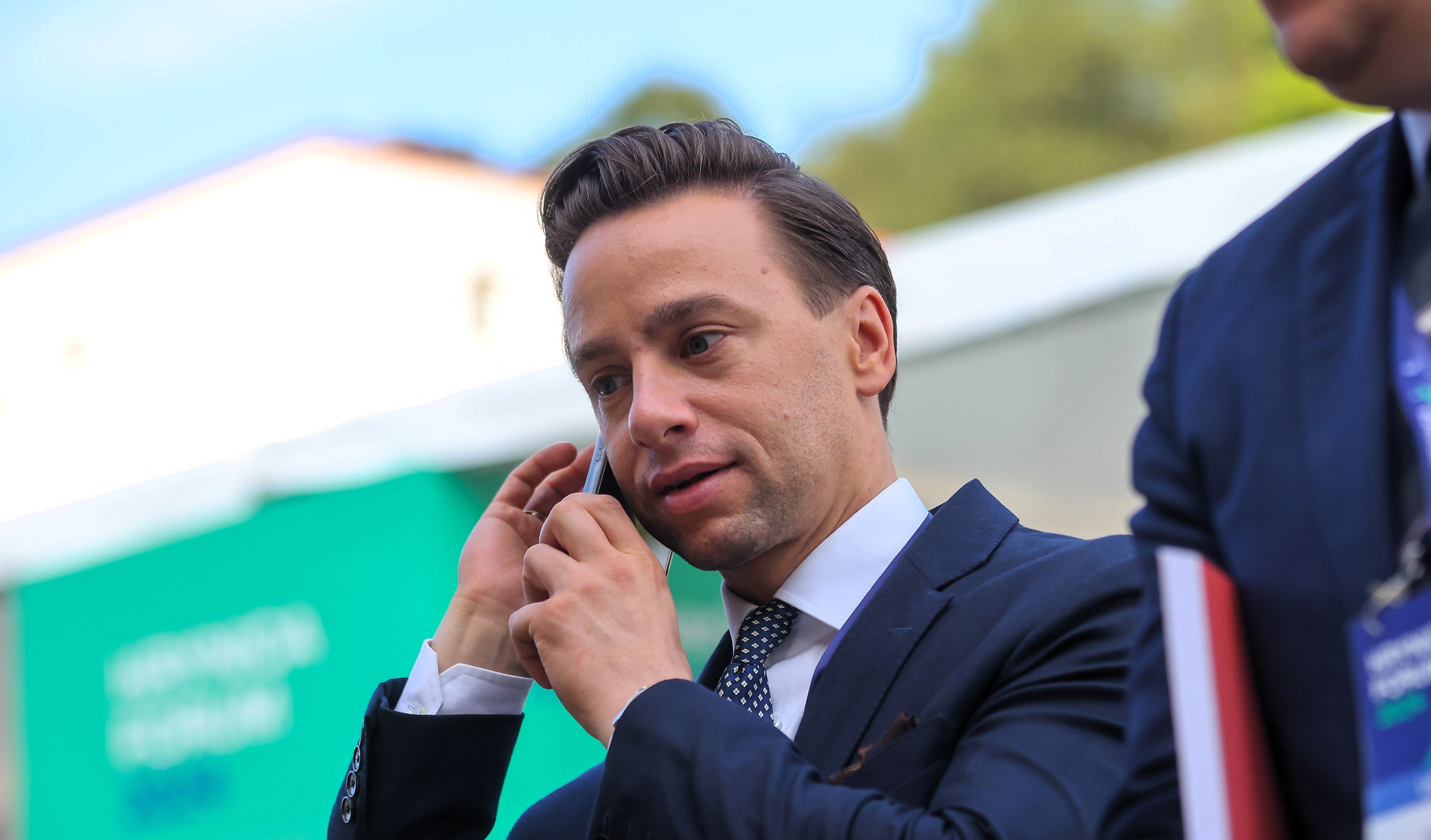Mężczyzna na scenie rozmawia przez telefon komórkowy zasłaniając usta reką