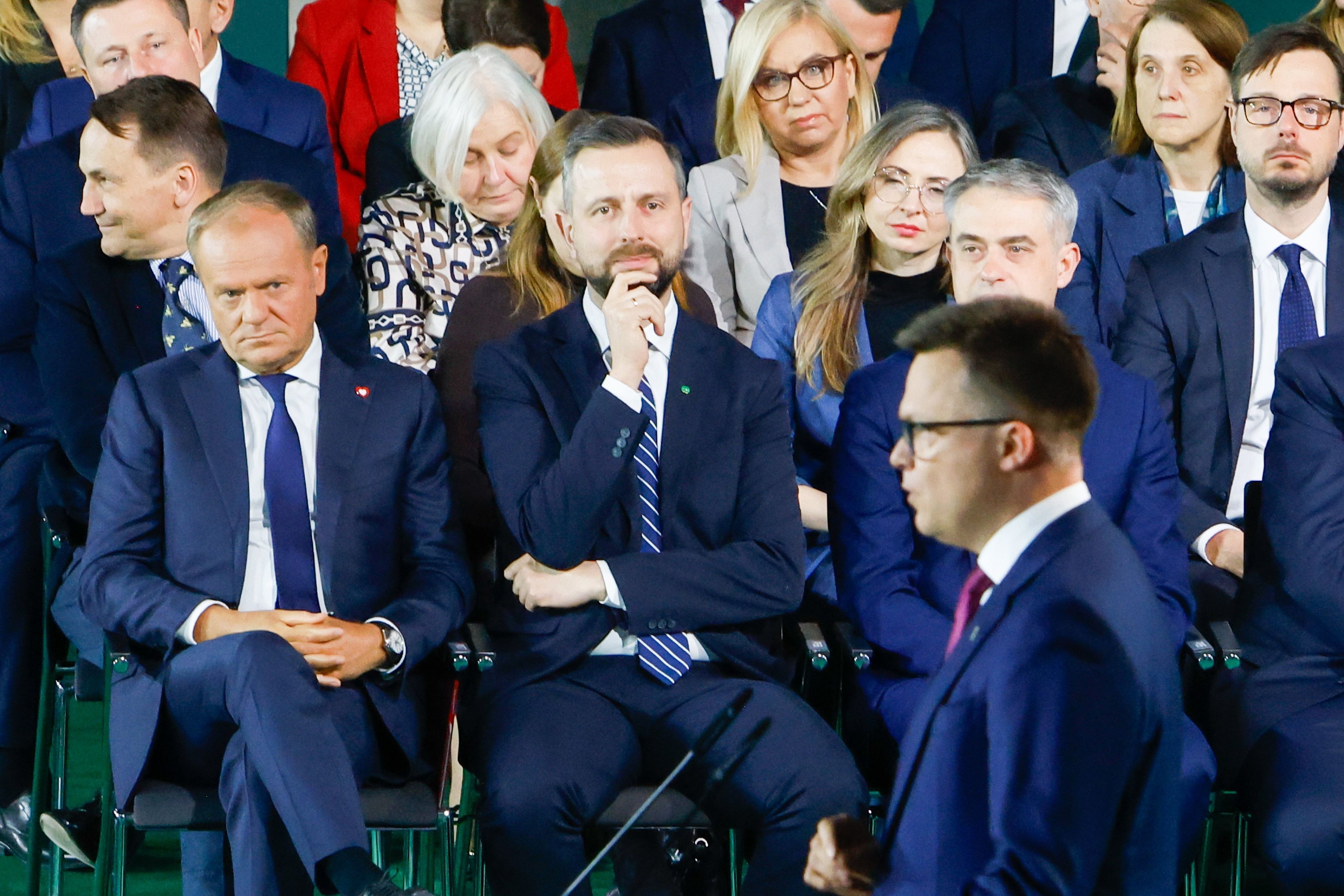 Widok pełnej sali, w pierwszym rzędzie siedzą liderzy rządzącej koalicji. Przed nimi stoi i przemawia marszałek Sejmu
