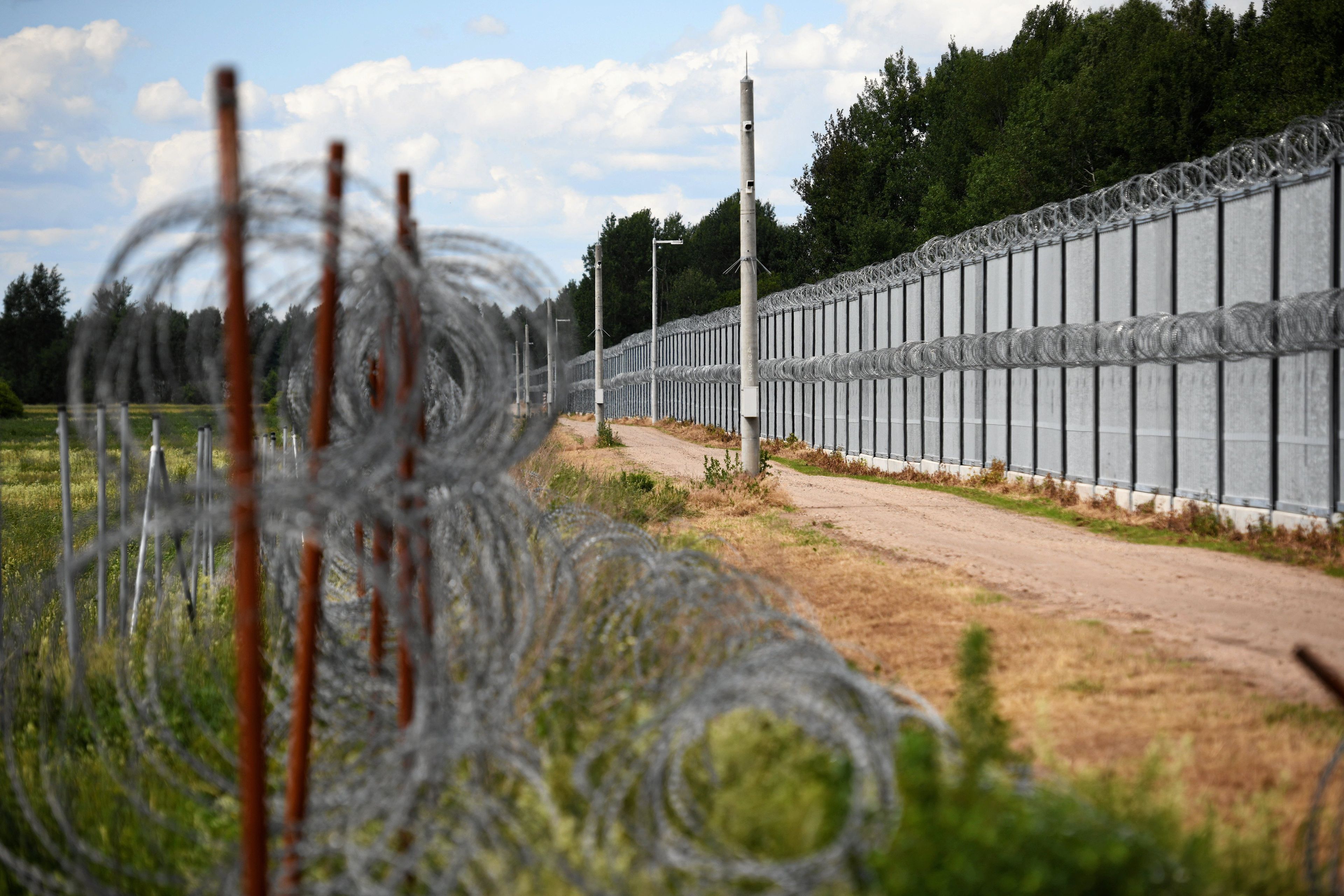 Granica z żelaznym płotem i spiralami drutu żyletkowego