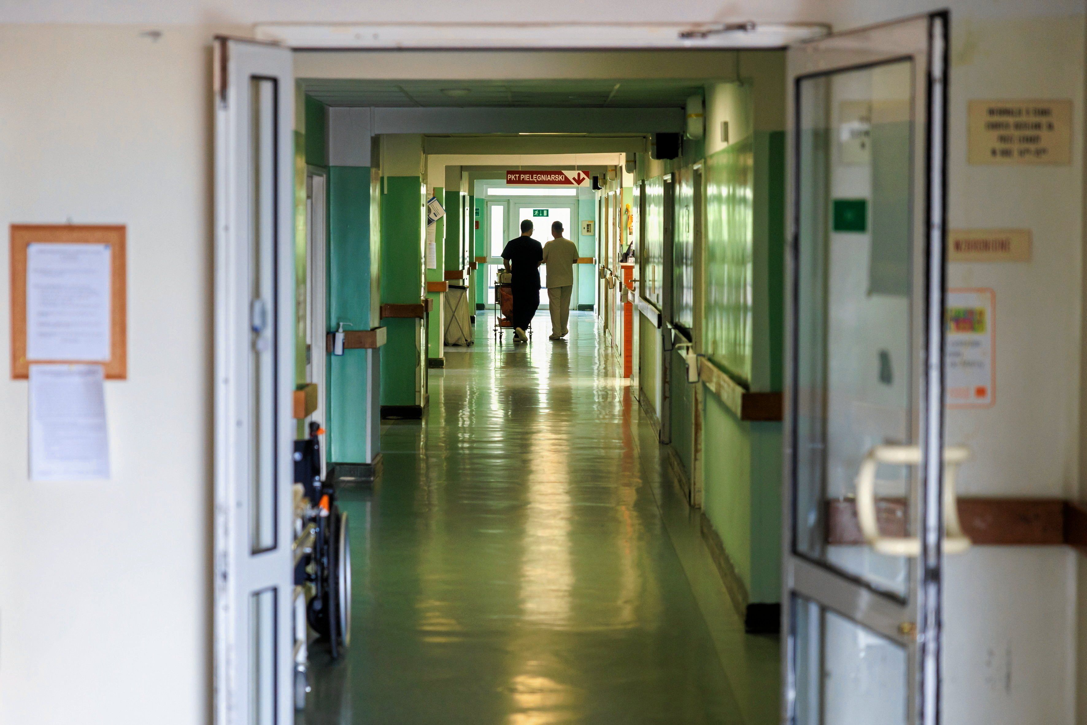 Dwie osoby widocznie w głębi długiego korytarza szpitalnego