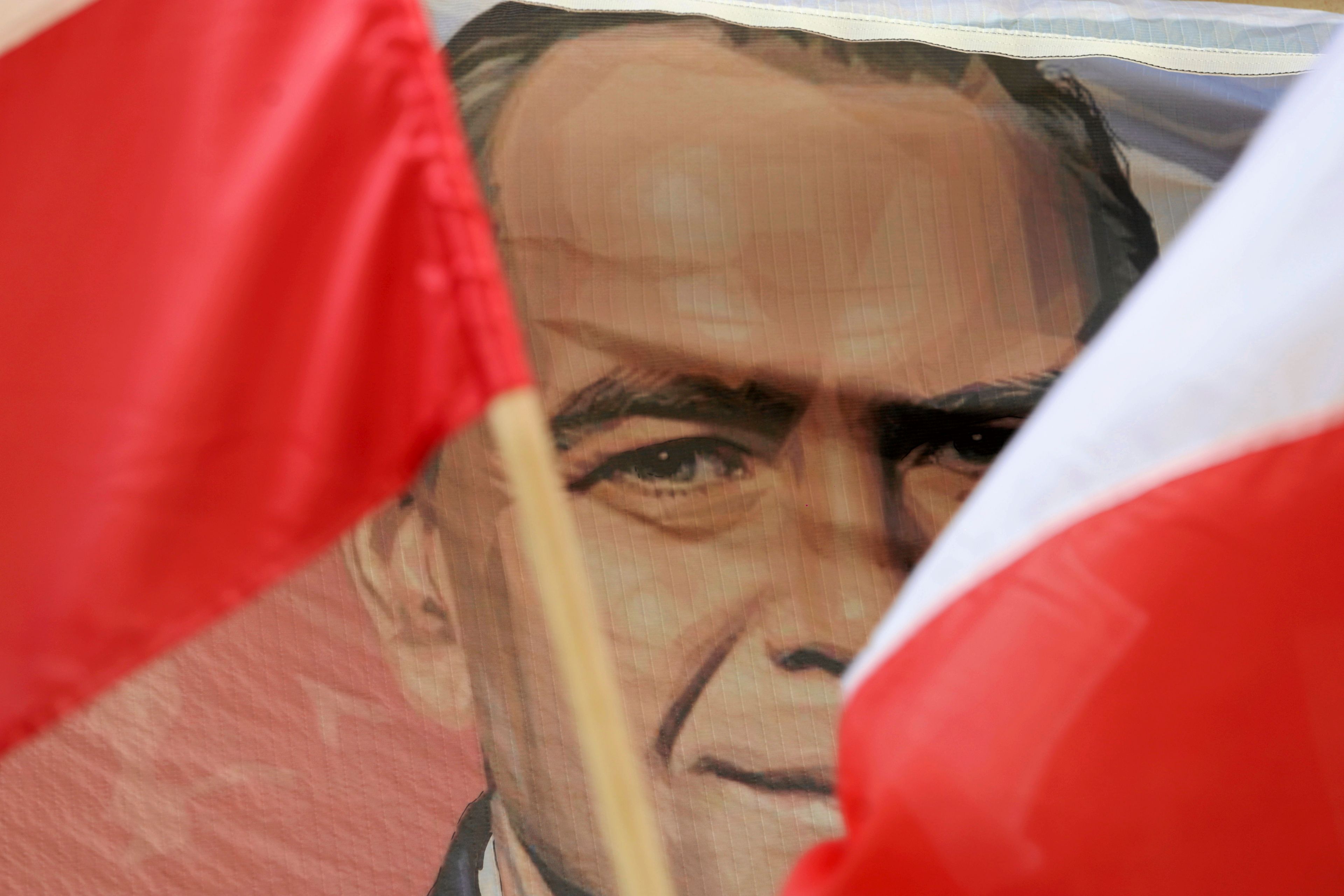 Dwie flagi narodowe spoza których widać podobiznę mężczyzny