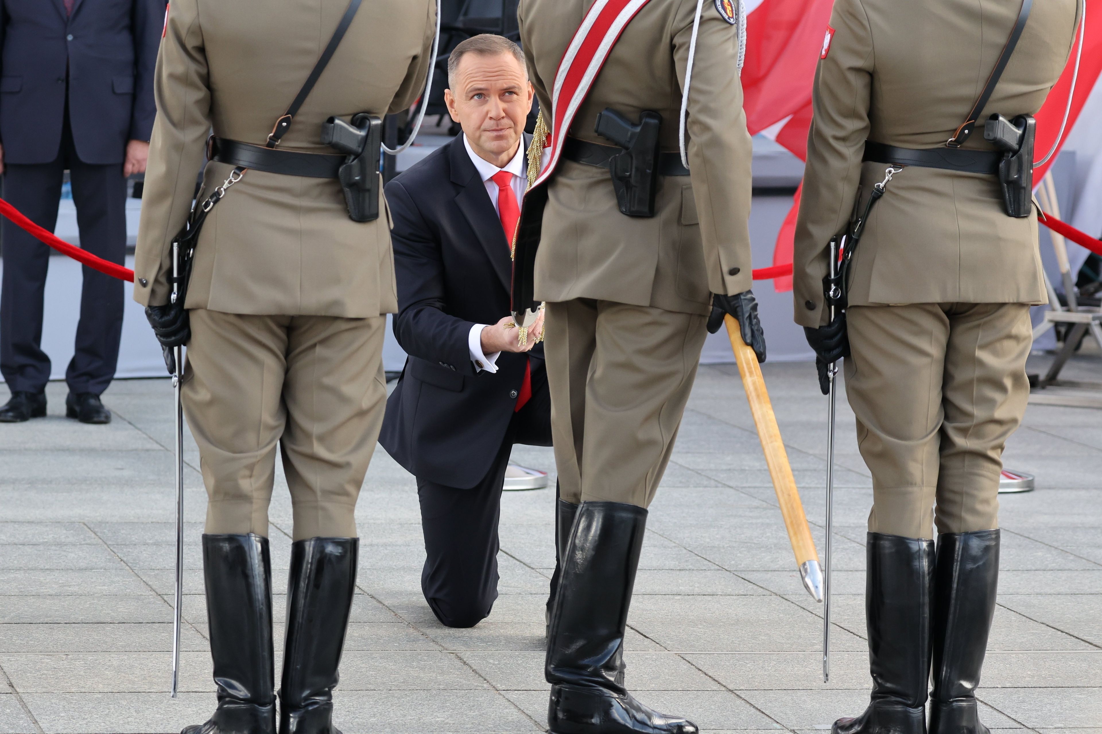 Karol Nawrocki klęka. W pierwszym planie żołnierze Wojska Polskiego