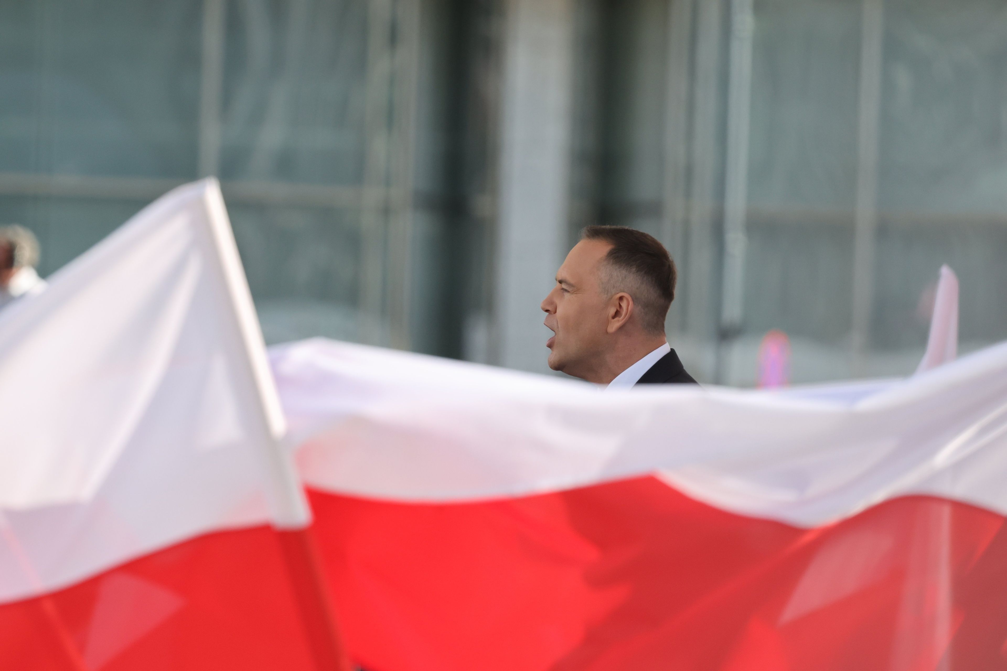 Nad białoczerwonymi flagami wystaje głowa mężczyzny