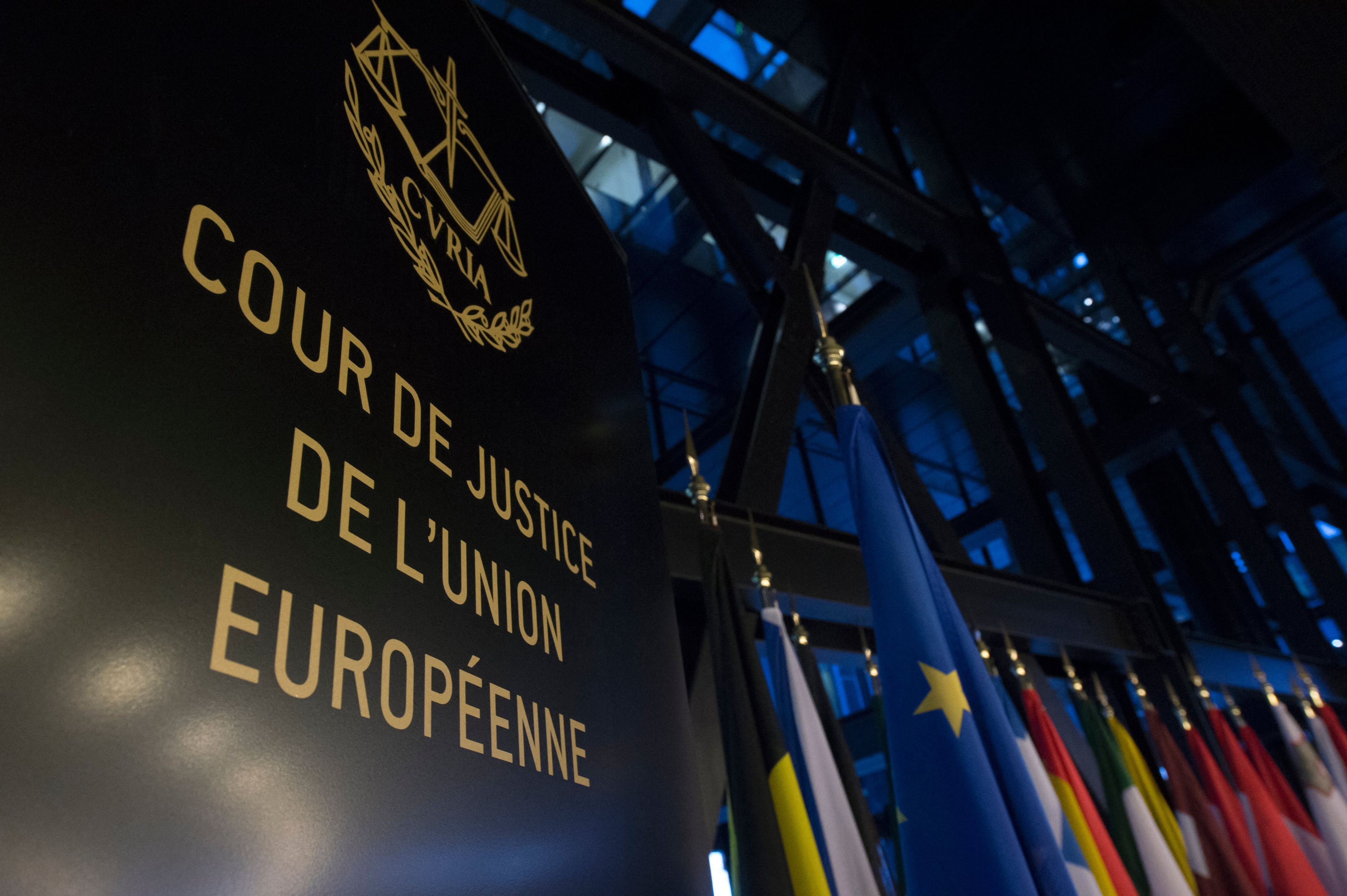 Zdjęcie Trybunału Sprawiedliwości Unii Europejskiej w Luksemburgu. Nazwa sądu po francusku obok flagi państw UE