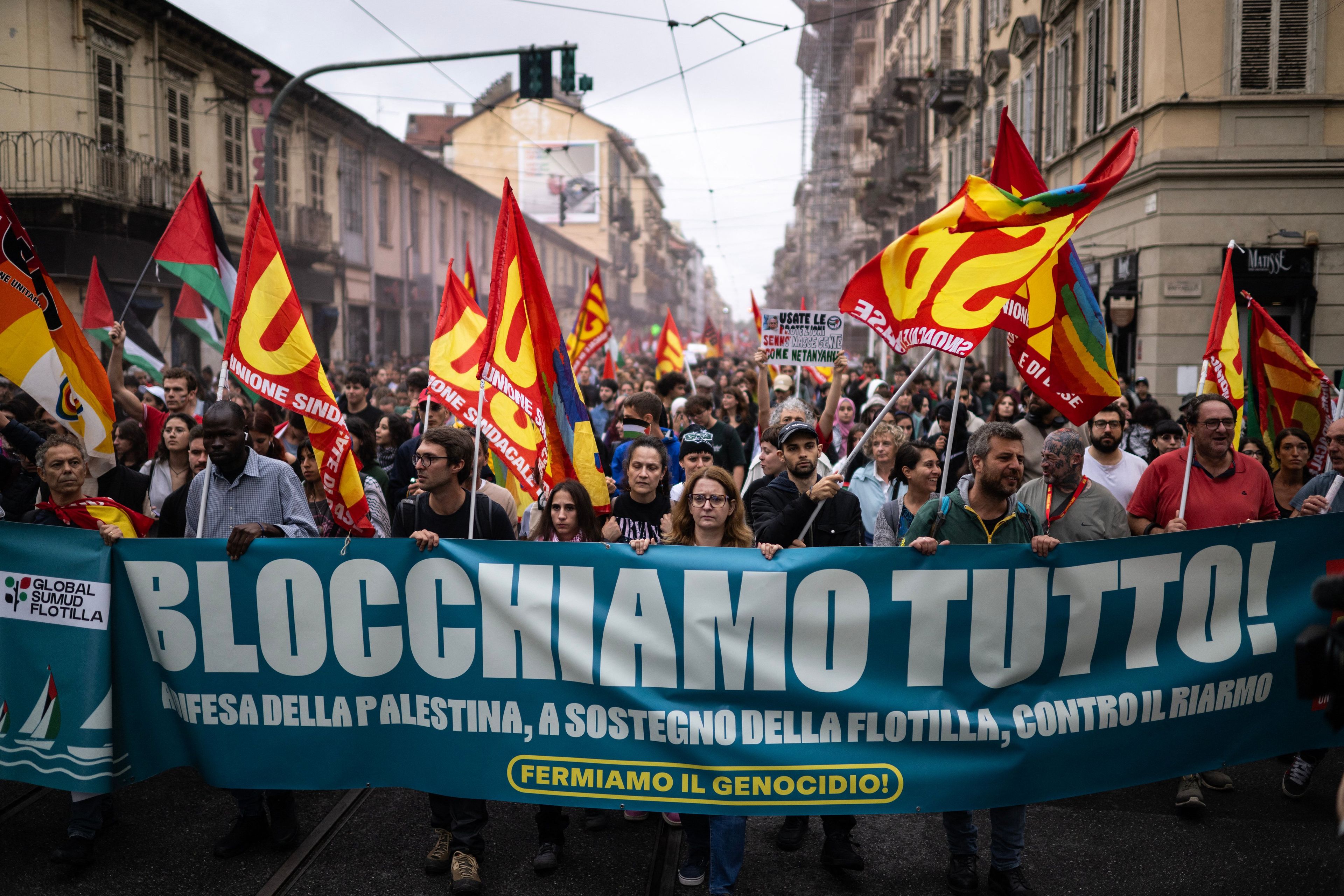 Demonstranci z transparentem po włosku "Blocchiamo tutto" ida szeroka ulicą
