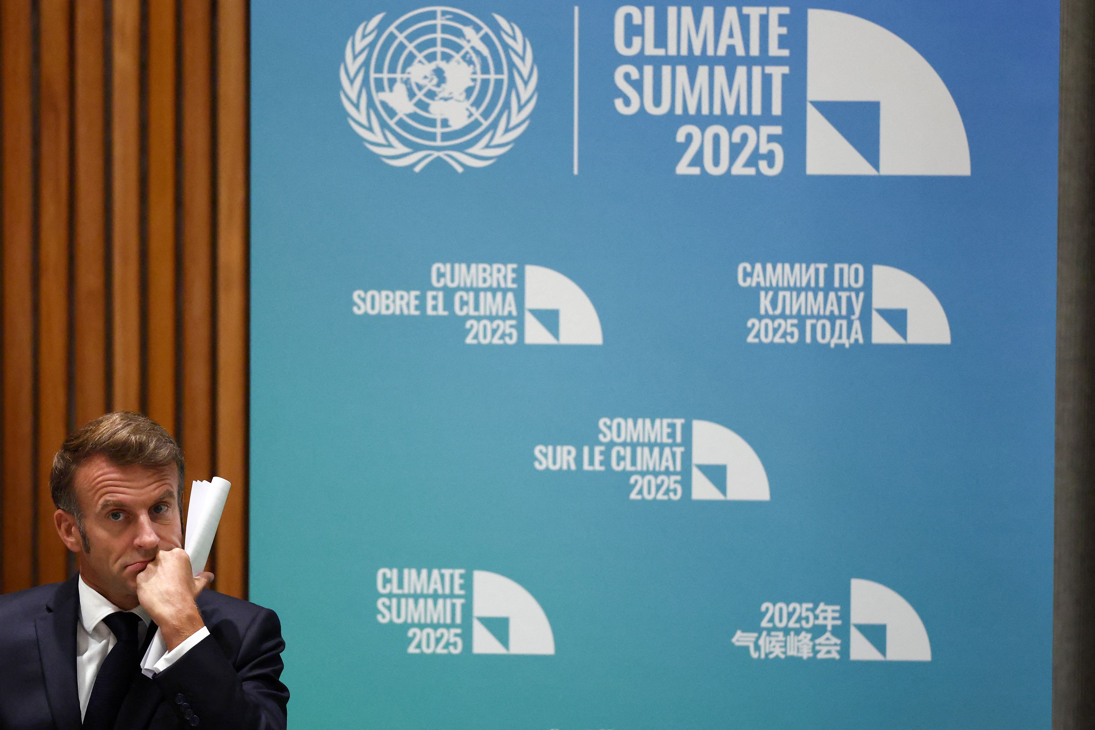 Ścianka z napisem „Global Climate Summit", z boku zmęczony mężczyzna w garniturze ze zwiniętymi papierami w ręku.
