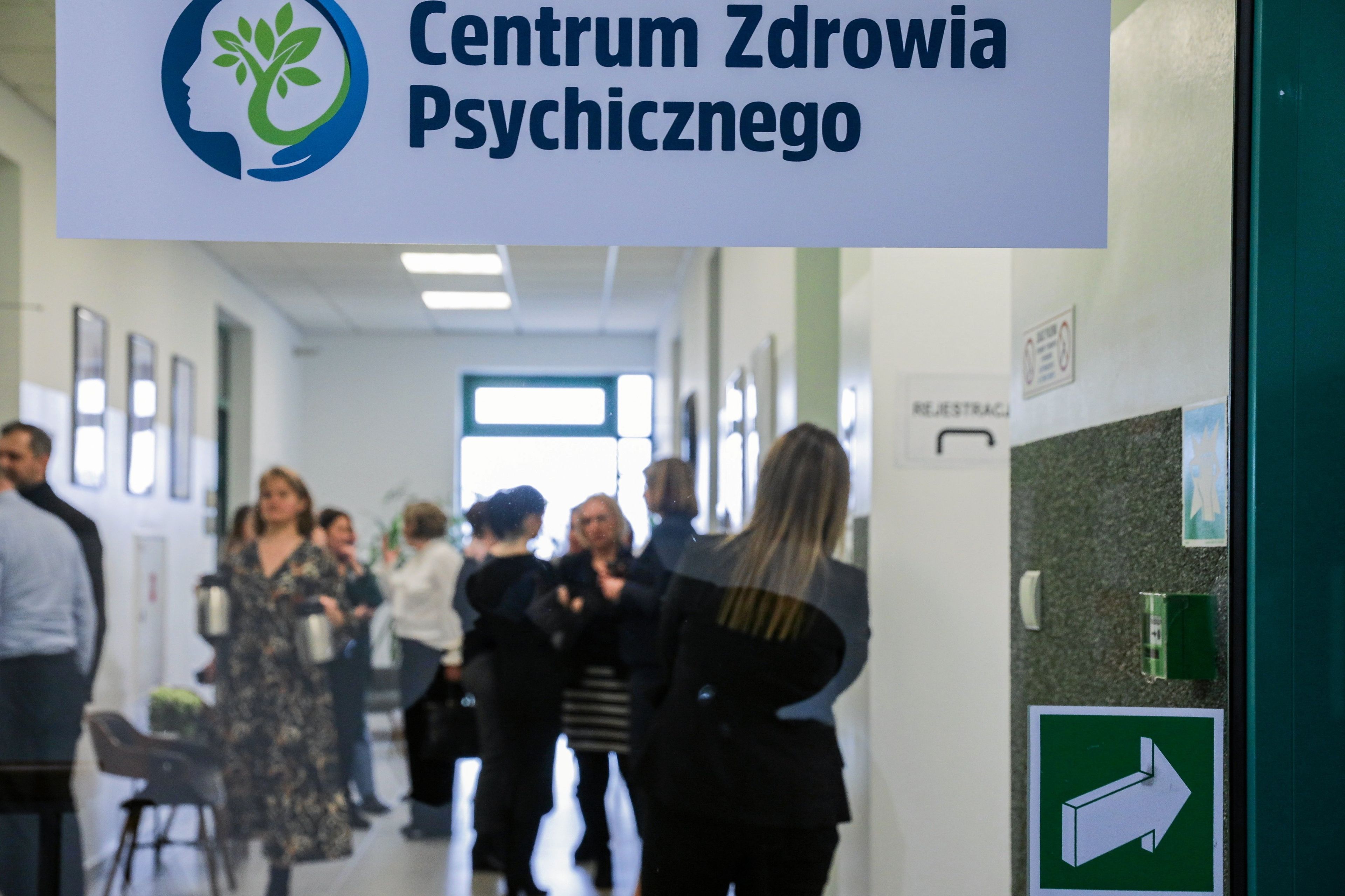 Korytarz pełen ludzi. Na górze tablica "Centrum Zdrowia Psychicznego"