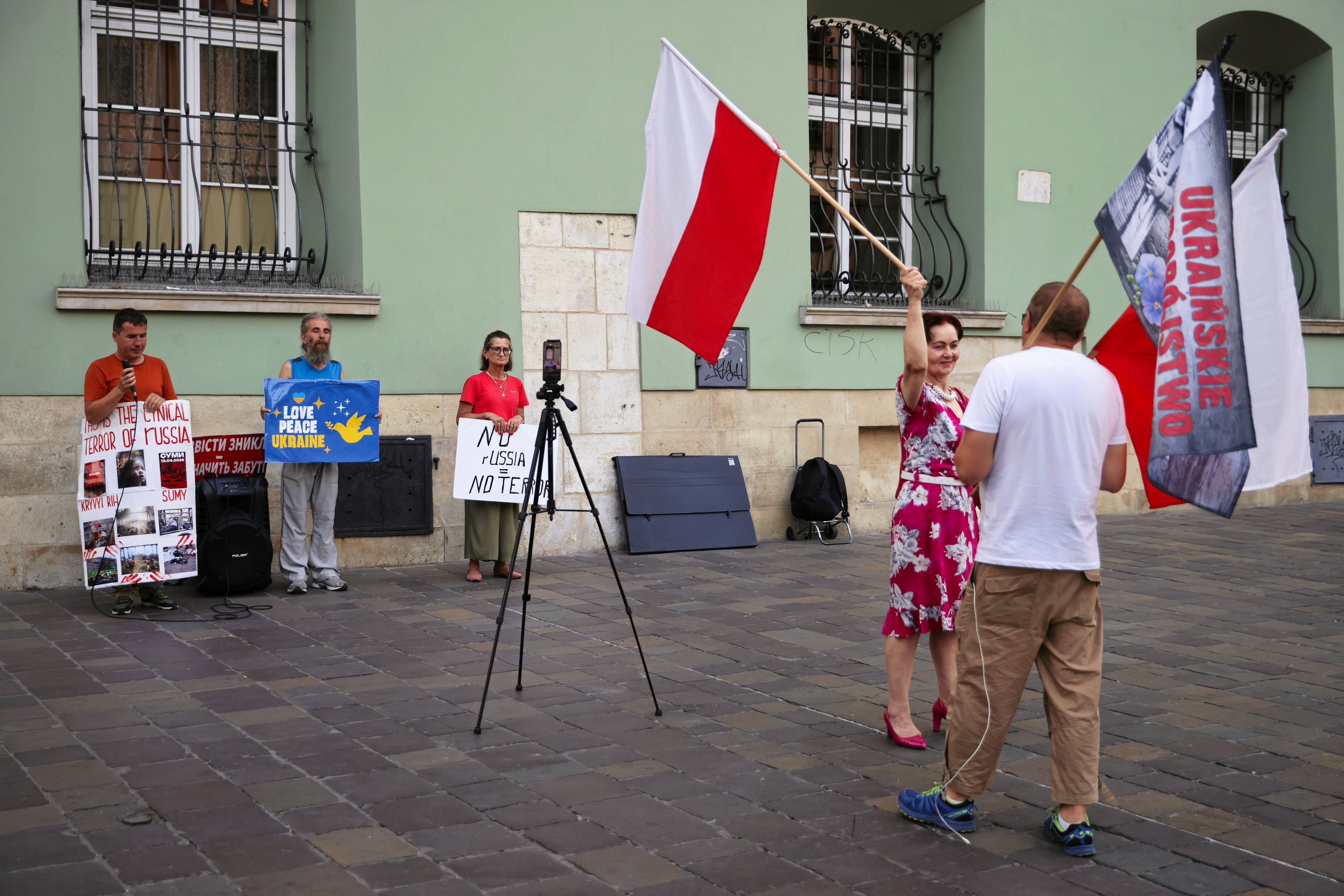 Ludzie z polskimi flagami i hasłami o „ukraińskim ludobójstwie" zasłaniają na ulicy trzy osoby z hasłami proukraińskimi.