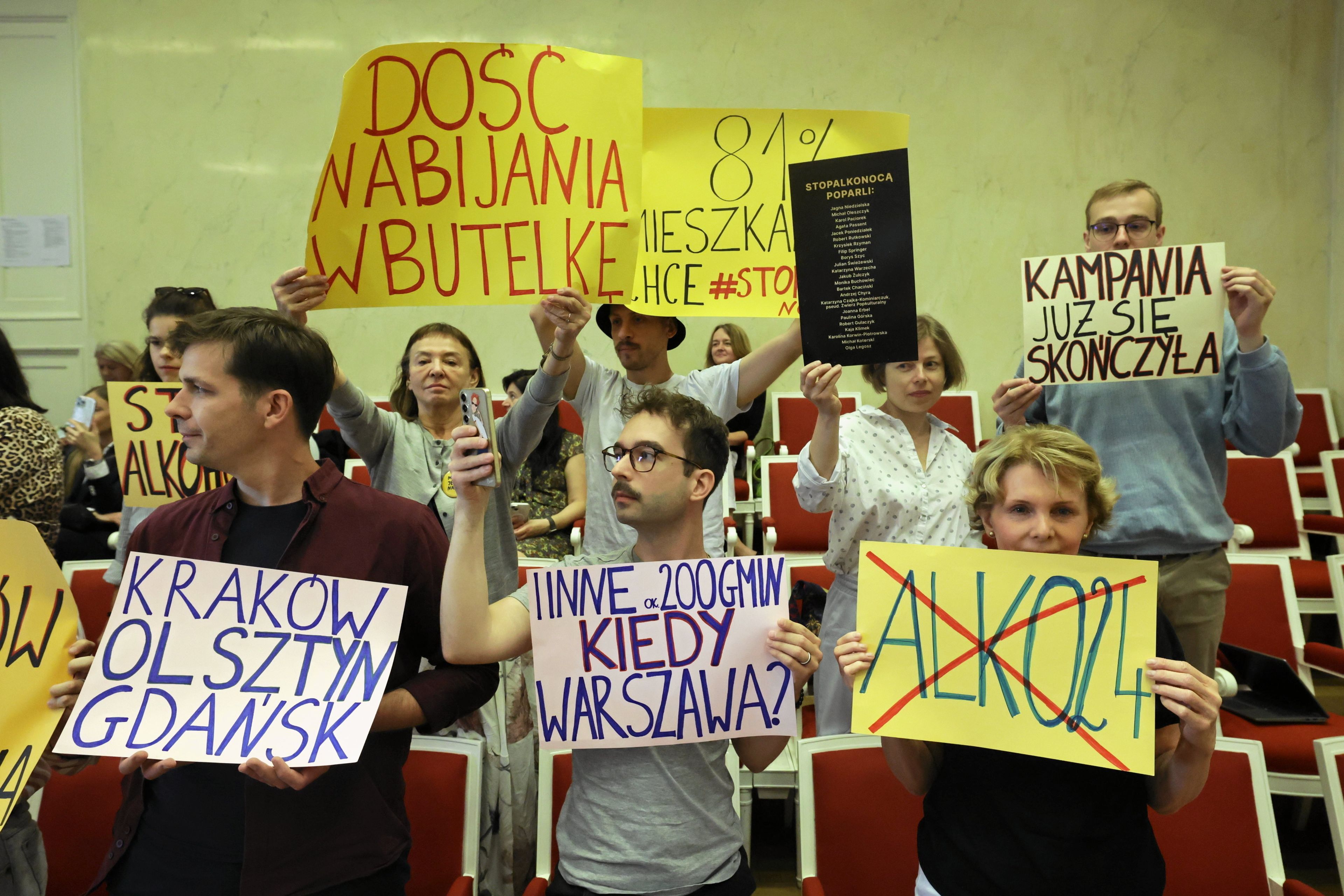 protest mieszkańców w radzie miasta, stoją z banerami nawołującymi do wprowadzenia zakazu sprzedaży alkoholu w nocy