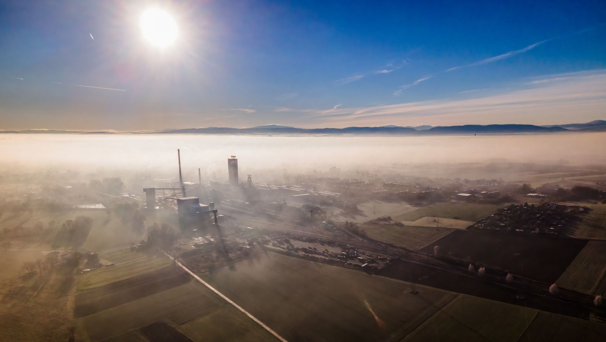 Widok z góry na miasteczko z szybami kopalnianymi. Na jednym mały napis "Piast". Wszystko zanurzone jest we mgle.