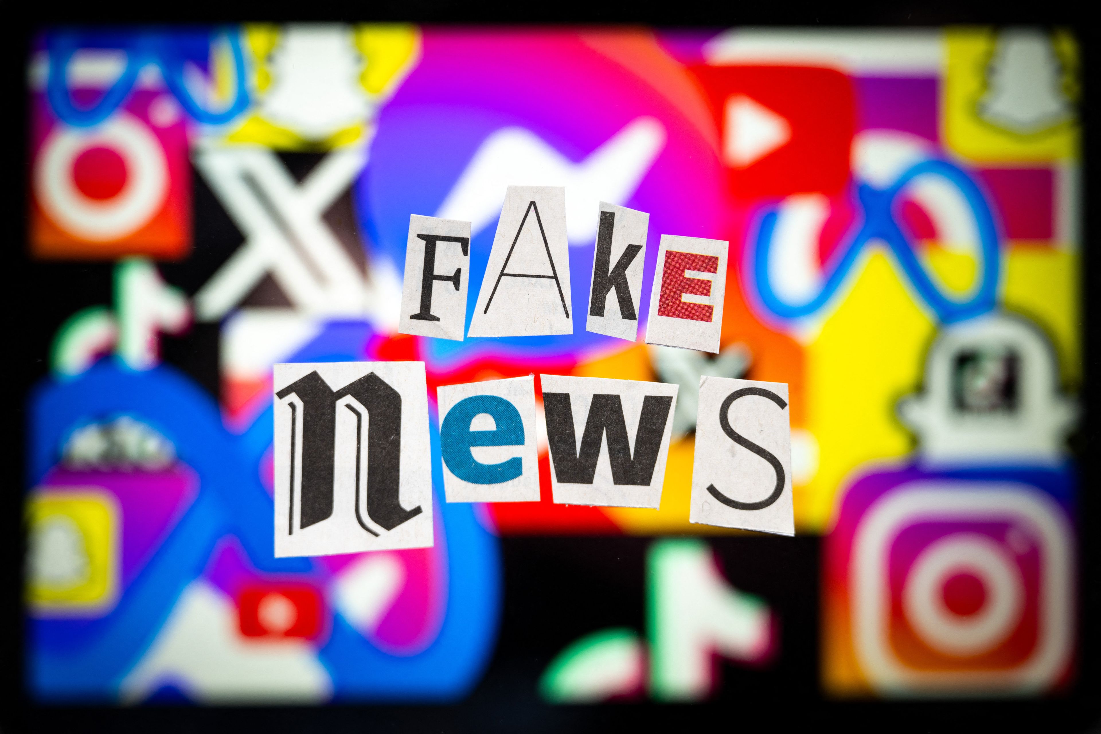 Kolaż z napisem FAKE News ułożonym z liter wyciętych z gazet, w tle loga mediów społecznościowych.