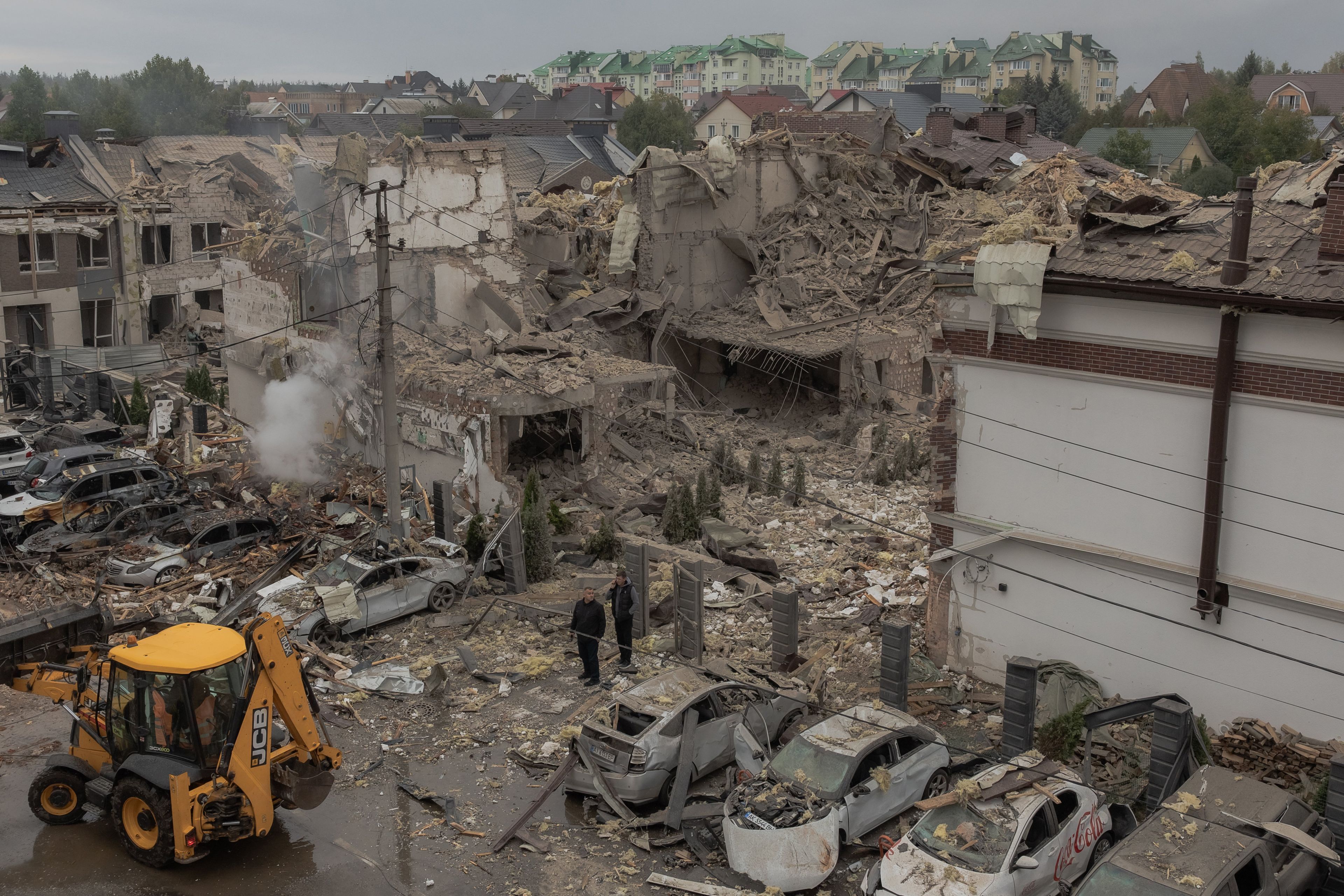Men stand at the site of heavily damaged residential buildings following a Russian air attack on the outskirts of Kyiv, on September 28, 2025, amid the Russian invasion of Ukraine. An overnight Russian barrage on Kyiv killed at least four people, including a 12-year-old girl, Ukrainian authorities said on September 28, 2025. (Photo by Roman PILIPEY / AFP)