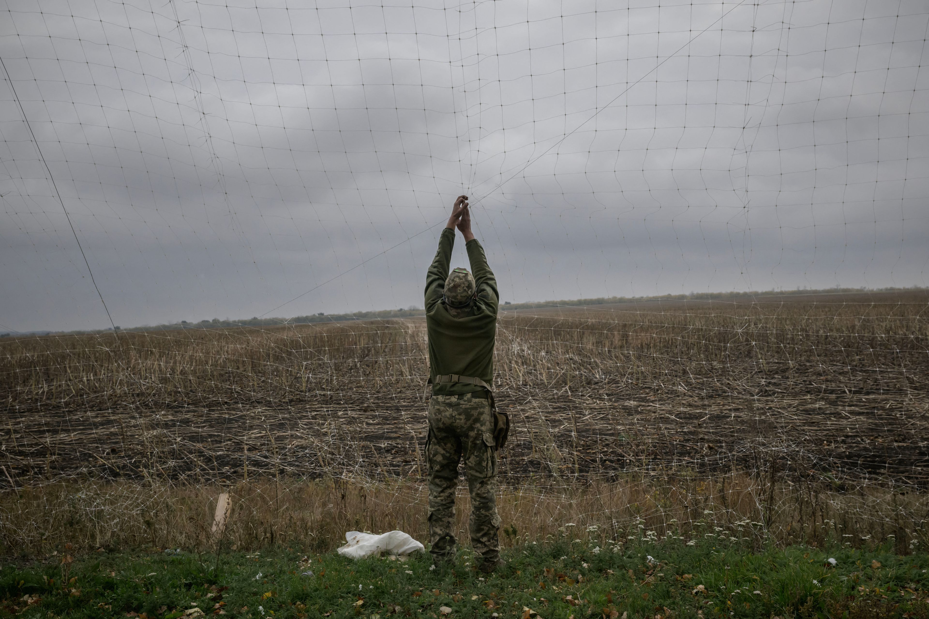 Żołnierz montujący siatkę przeciwdronową.