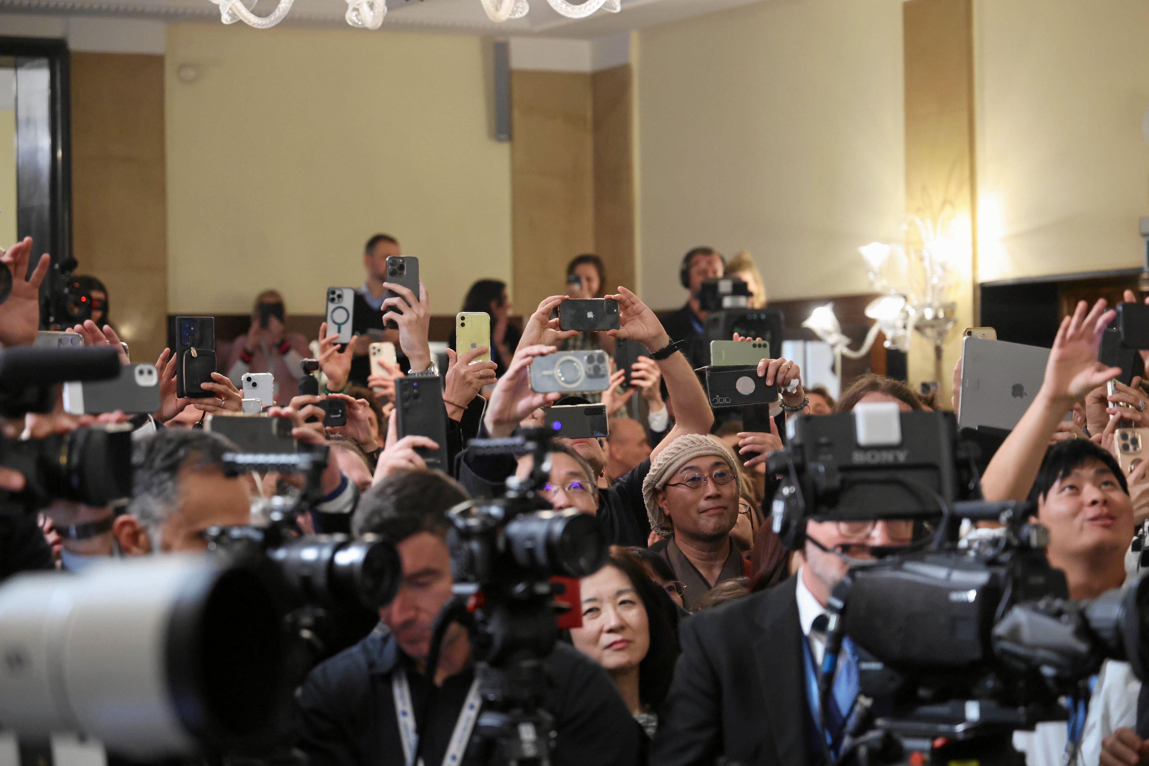 Tłum ludzi z wystawionymi do fotografowania telefonami komórkowymi