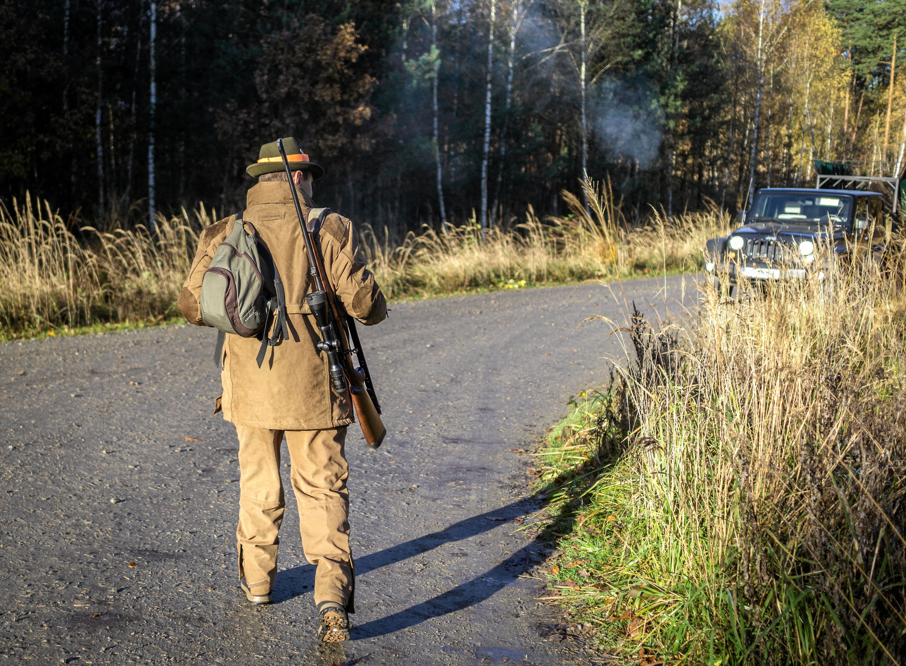 myśliwy w bronią stoi tyłem do aparatu