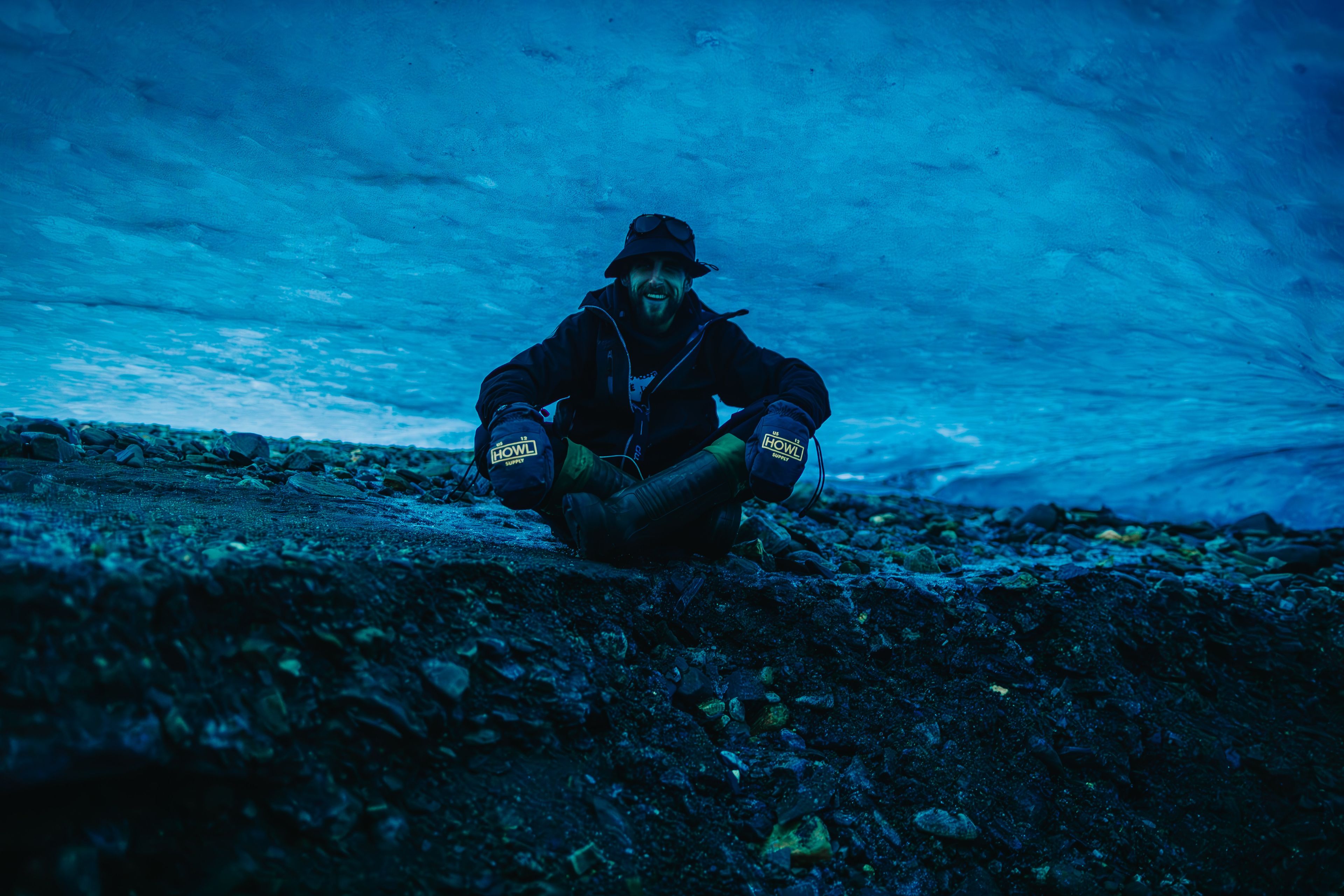 Uśmiechnięty młody mężczyzna siedzi w lodowej jaskini.