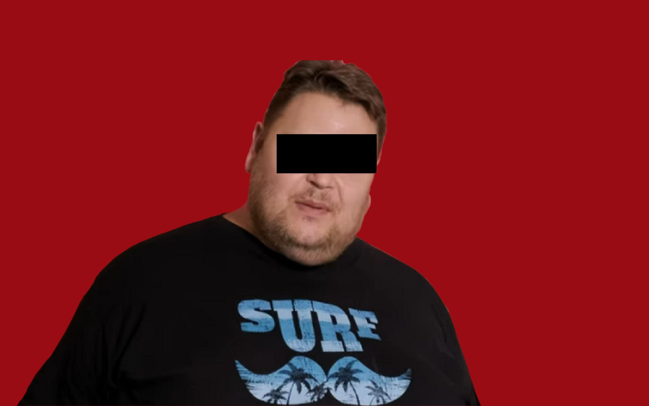 Mężczyzna w średnim wieku, w czarnym T-shircie z napisem, stoi na tle czerwonej ścianki