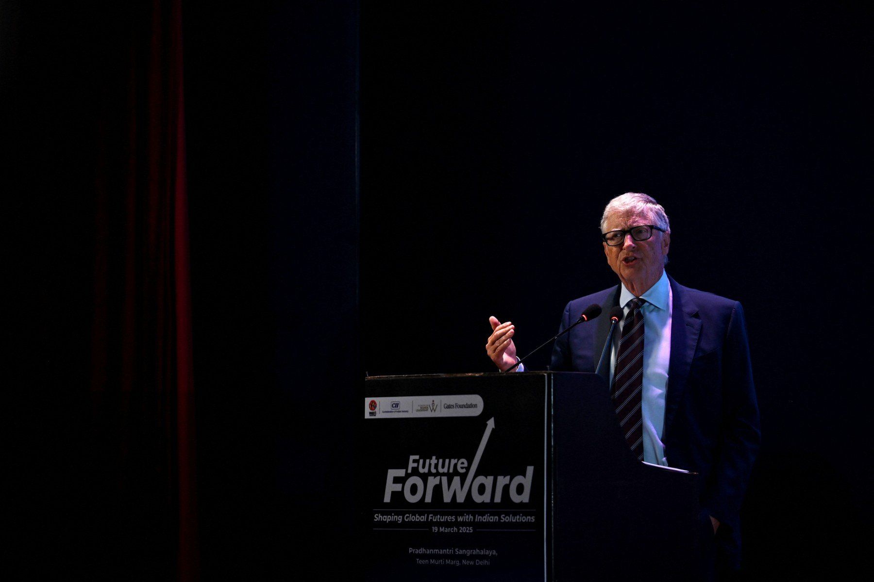 Bill Gates w garniturze na ciemnej scenie