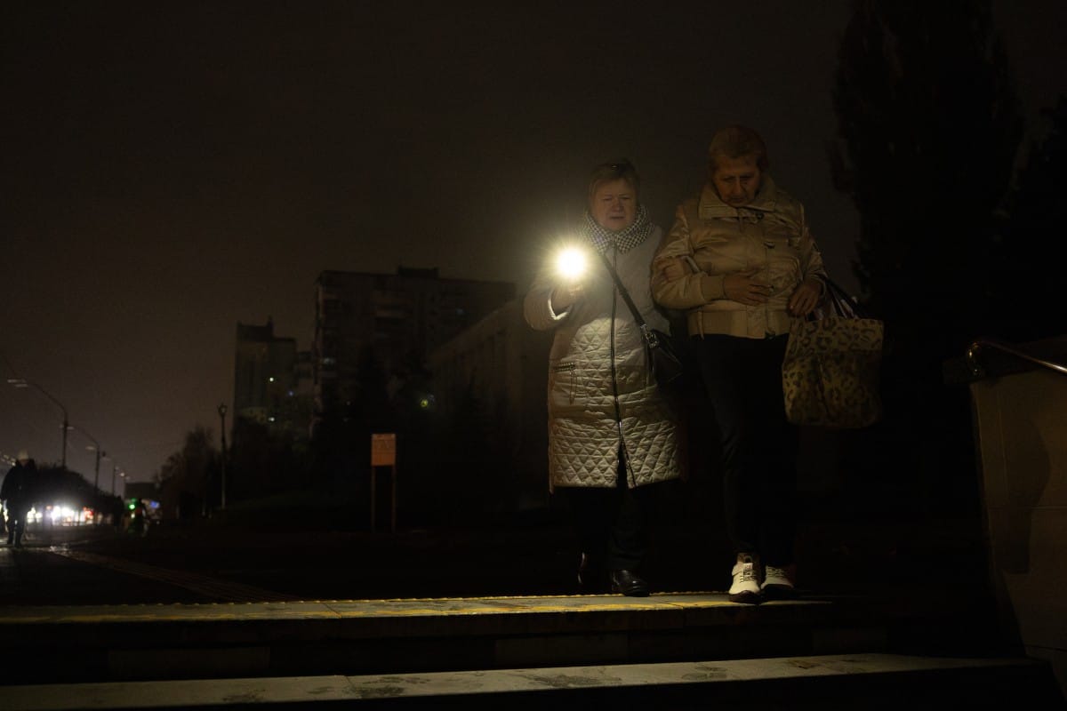 Women walk along a street during a blackout in Kyiv on November 9, 2025, following Russian missile and drone attacks on Ukrainian energy infrastructure. Ukrainian crews scrambled on November 9, 2025 to repair damage caused by one of the most devastating Russian attacks on Ukraine's energy infrastructure, President Volodymyr Zelensky said. Moscow, which has escalated attacks on Ukraine's infrastructure in recent months, launched hundreds of drones at energy facilities across the country overnight into November 8, 2025. (Photo by Roman PILIPEY / AFP)
