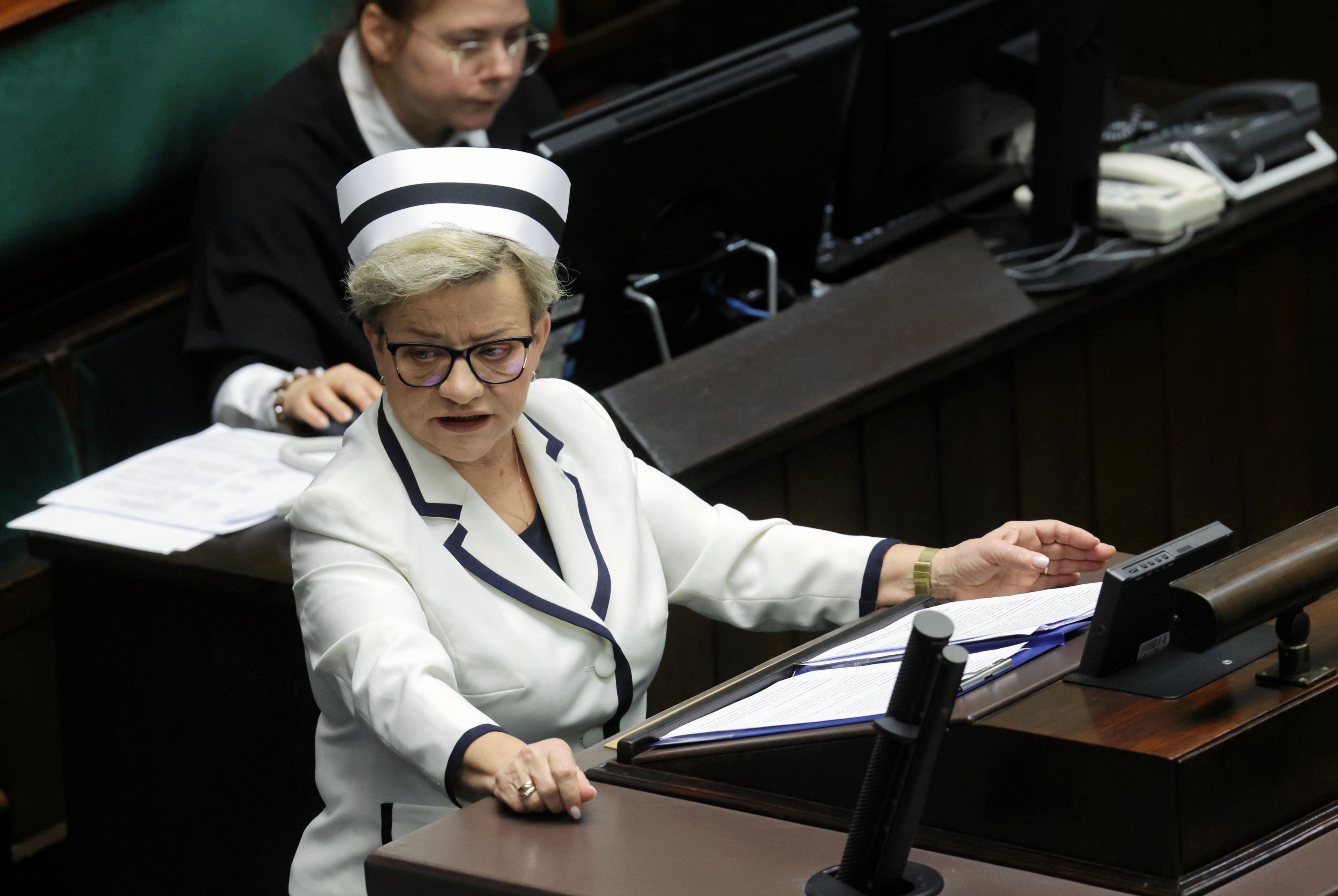 Kobieta w białym stroju pielęgniarskim na mównicy sejmowej