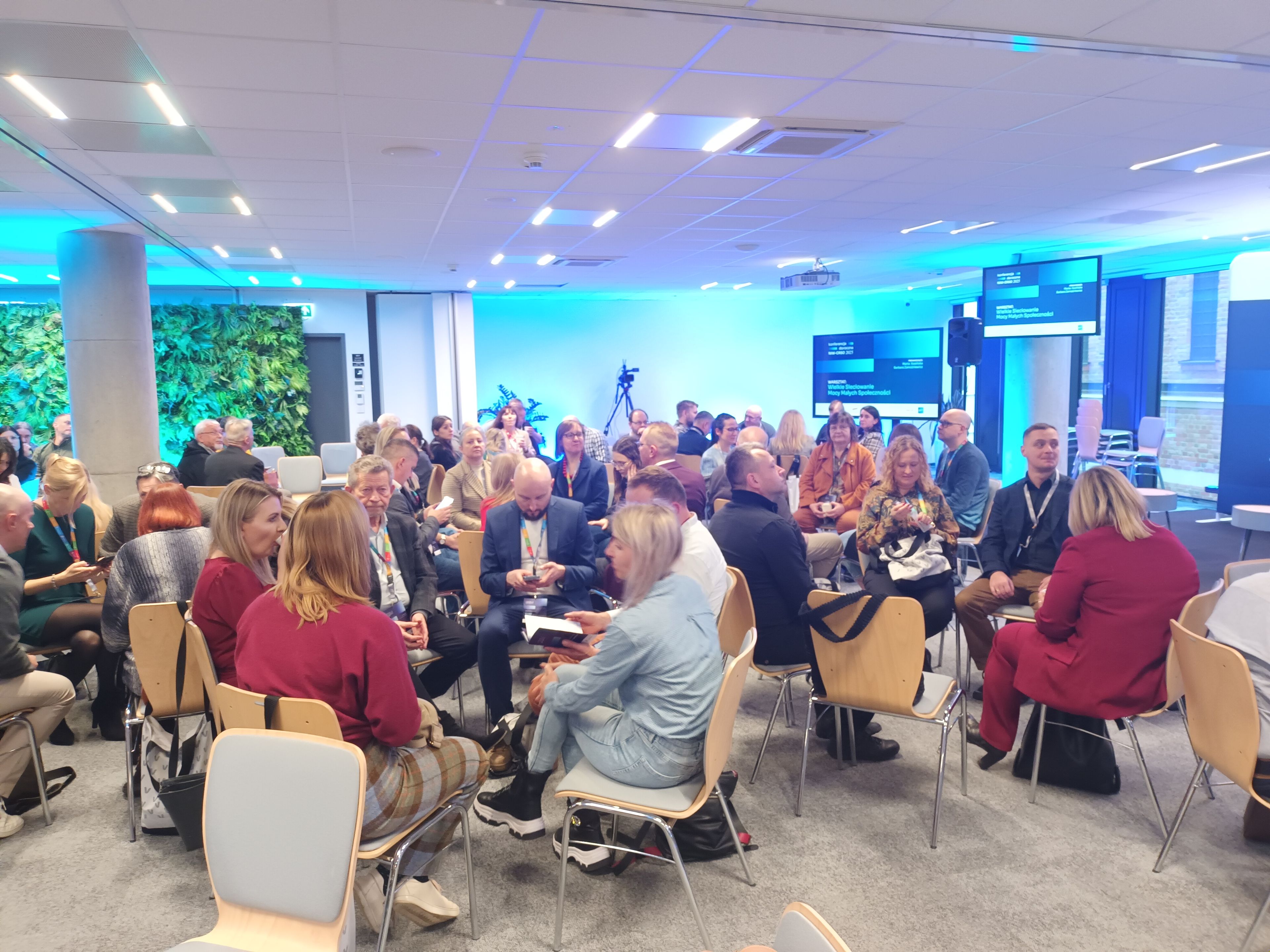 Ludzie siedza na sali w kręgach i rozmawiają