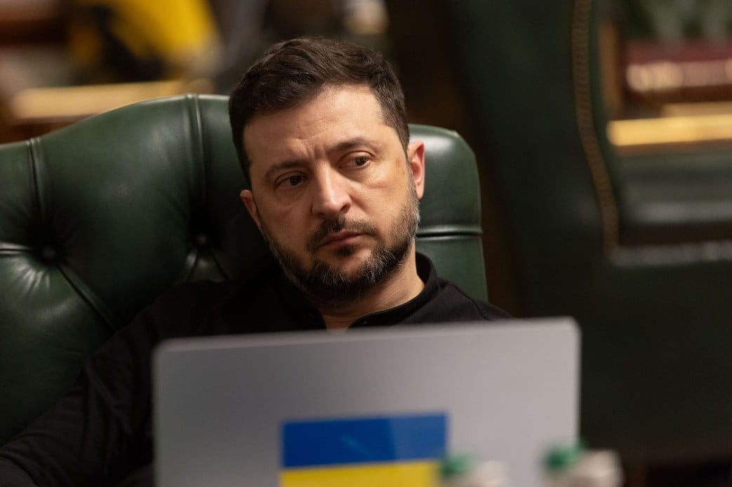 Na zdjęciu jest mężczyna ok. 45 lat, ma czarne włosy i brodę. Siedzi przedz szarym laptopem, na ktorym jest nakleika z flagą niebiesko-żółtą