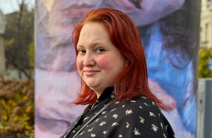 Magda patrzy prosto w obiektyw, ma rude włosy i czarną koszulę