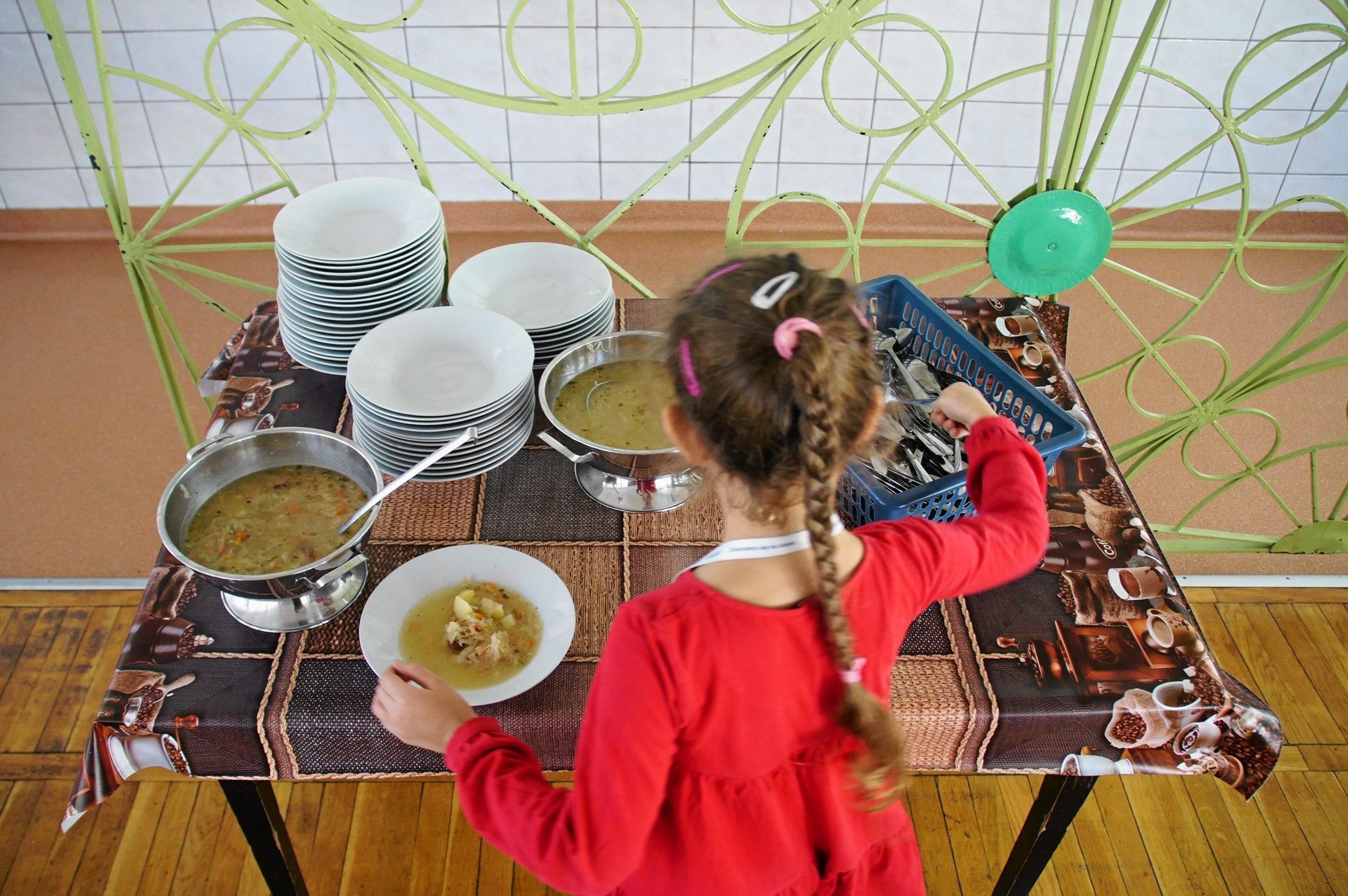 Dziewczynka nalewa sobie zupę w szkolnej stołówce