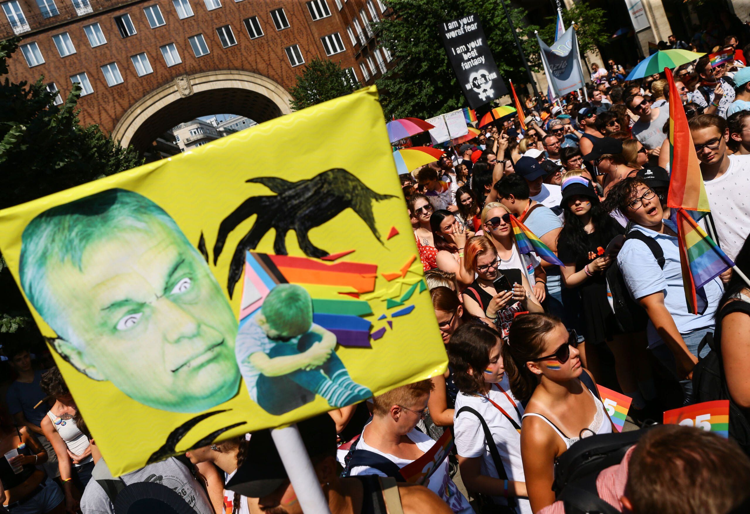 Ludzie na demonstracji z tranparentami z tarczą i podobizną Orbana